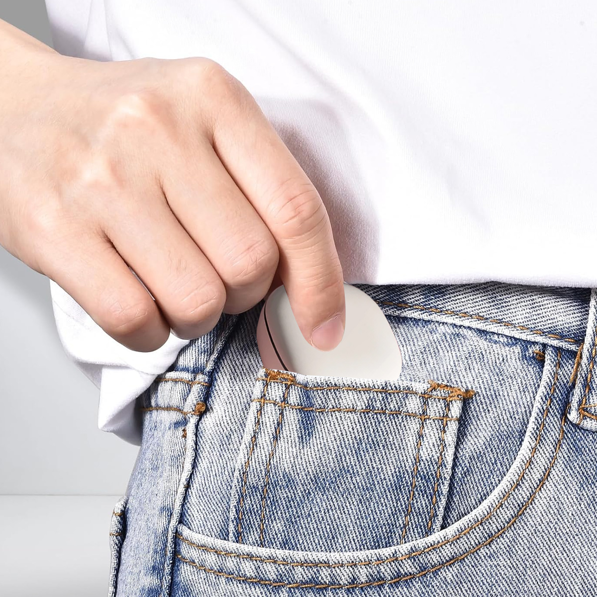 Eine Hand, die ein kleines weißes Schlafhilfegerät in eine Jeanshosentasche steckt.