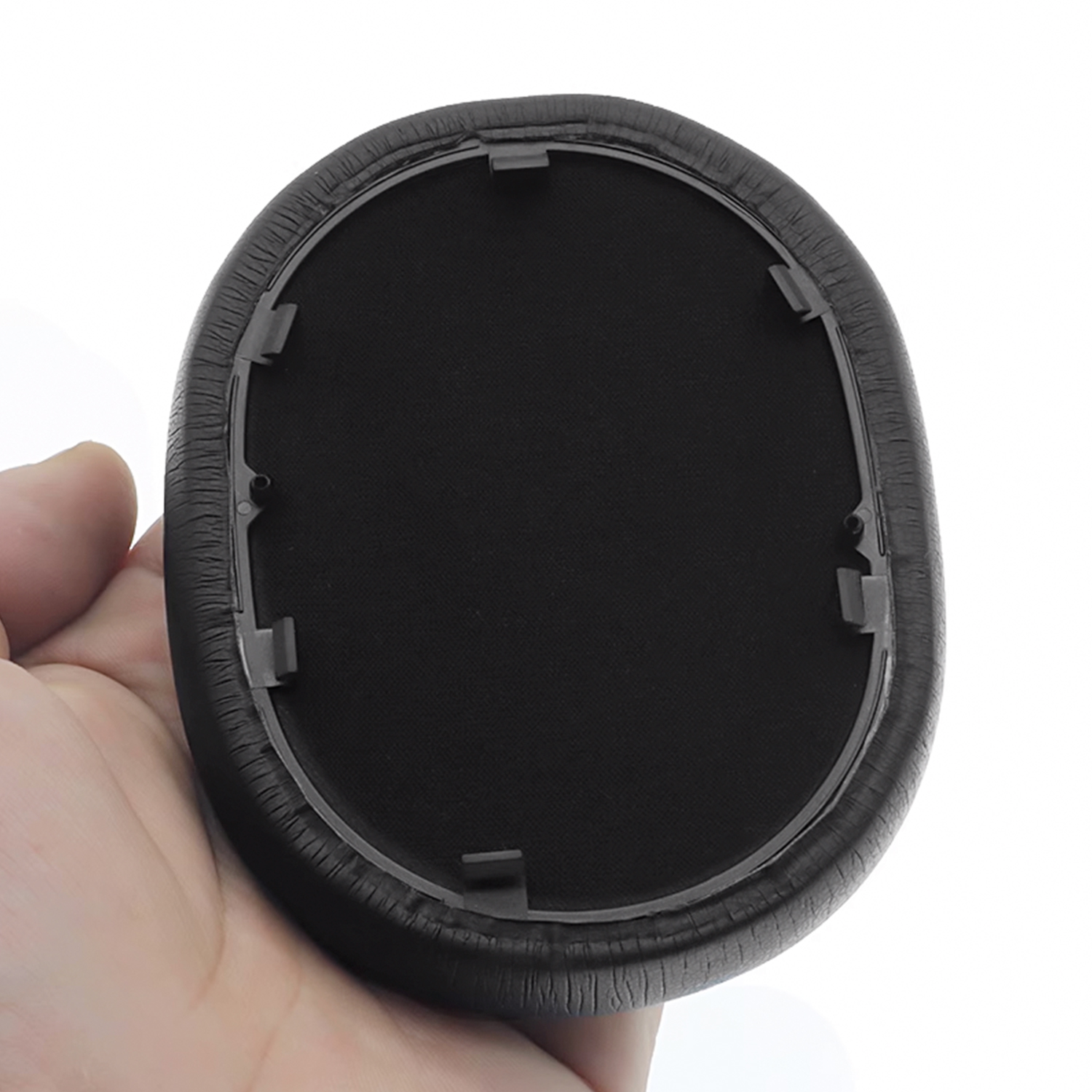 Ein schwarzes Ohrpolster für Kopfhörer, gehalten in einer Hand, weißer Hintergrund.