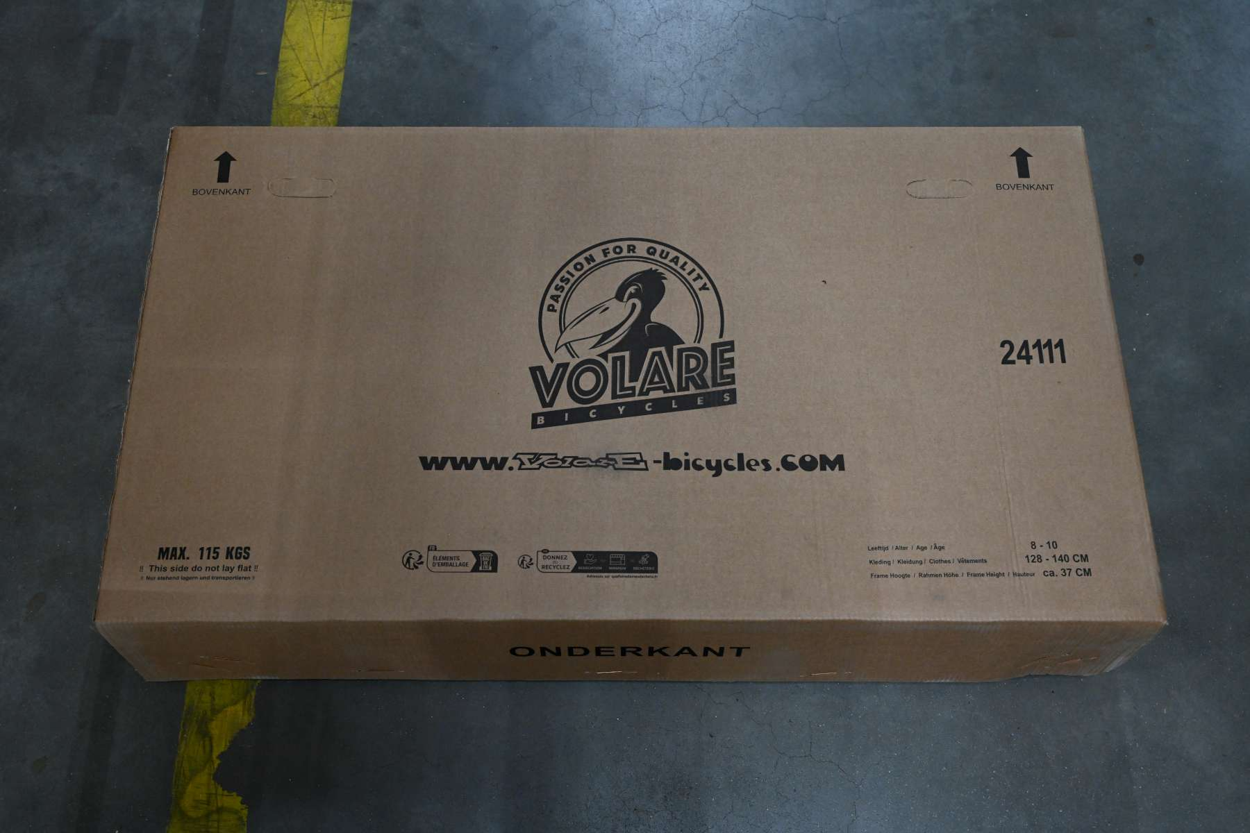 Ein Karton mit Text und Logos. Die Oberseite der Box ist sichtbar. Der Hintergrund ist ein grauer Boden.