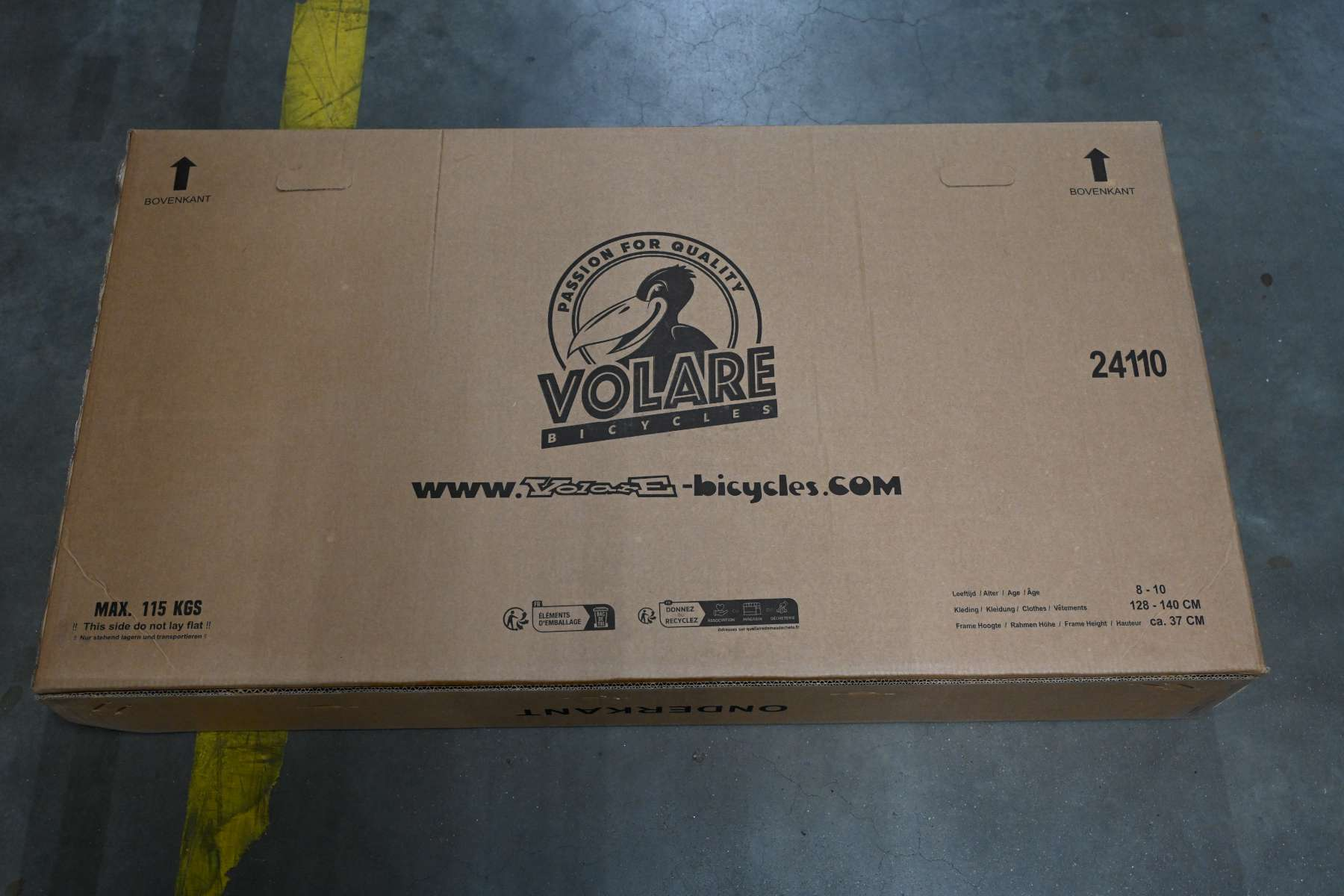 Ein Karton mit Text und Logos. Die Oberseite der Box ist sichtbar. Der Hintergrund ist ein grauer Boden.