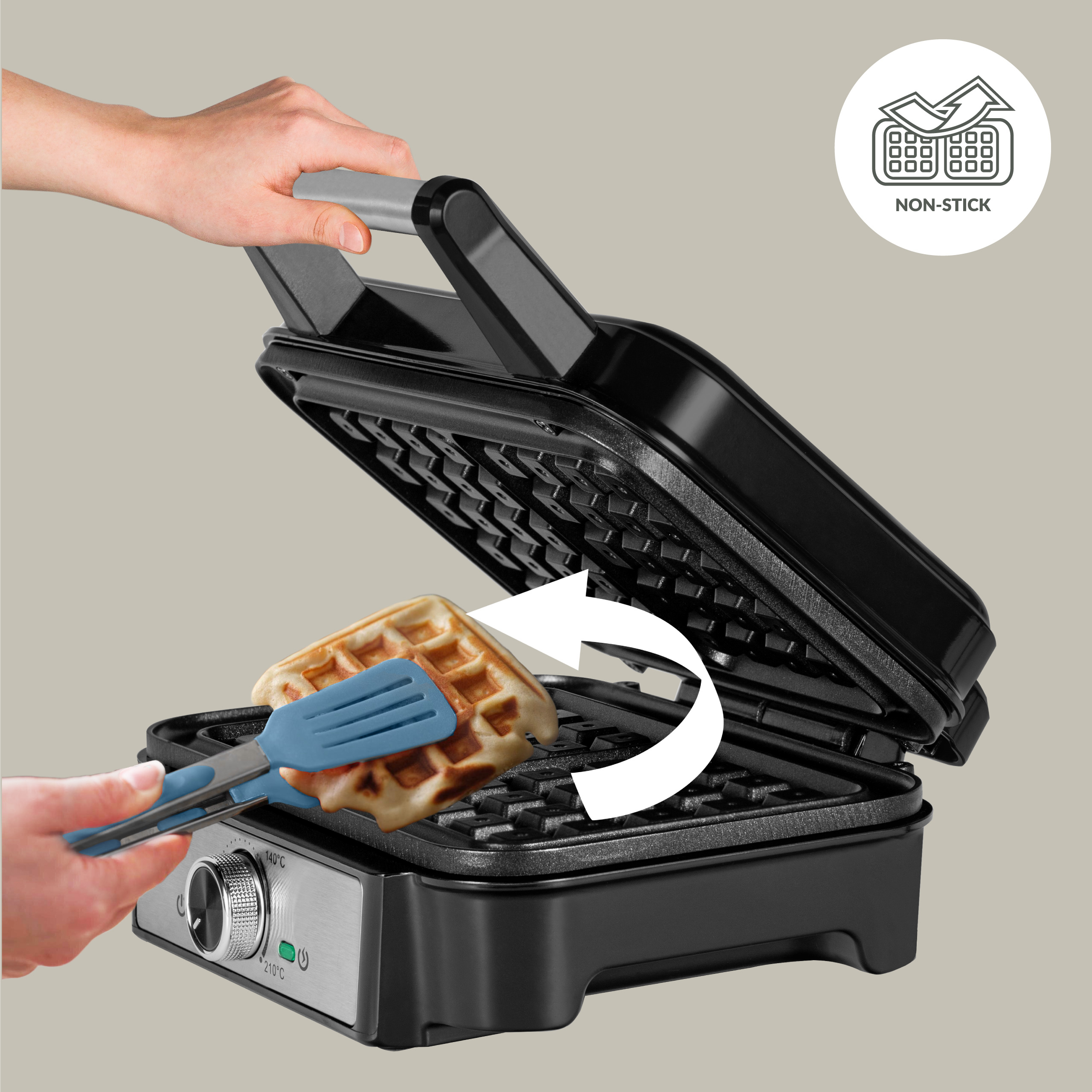 Gofrownica z gofrem i niebieską szpatułką. Ręka otwiera pokrywę.