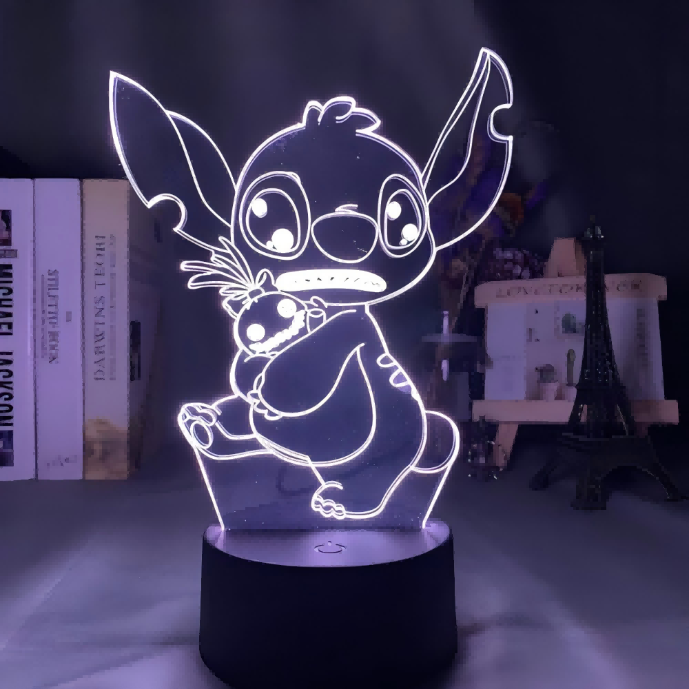 Eine Stitch-LED-Lampe leuchtet blau. Stitch hält eine Puppe. Hintergrund: Bücher, ein kleines Gebäude und ein Eiffelturm.