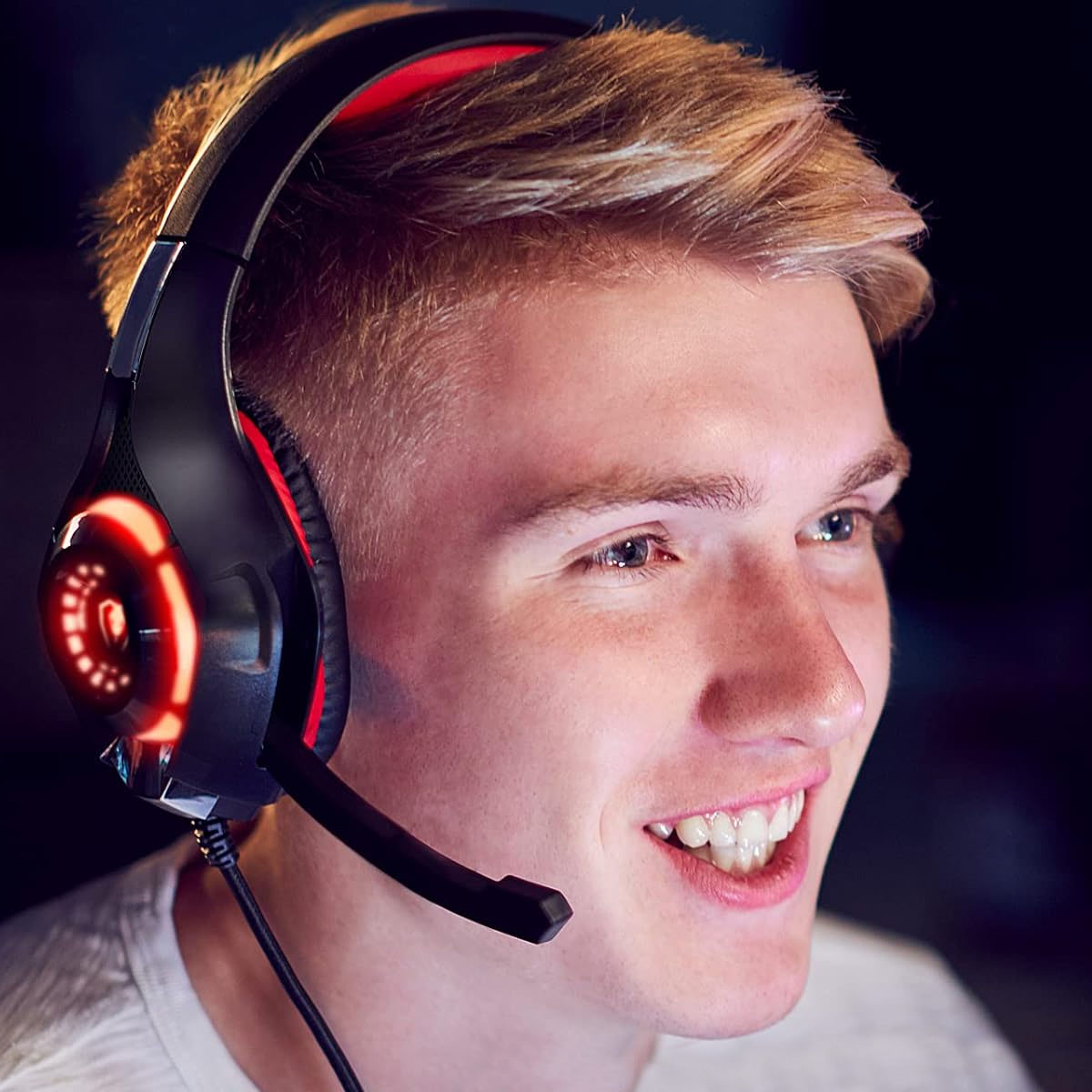 Junger Mann mit Gaming-Headset, lächelnd. Das Headset hat rote Lichter.