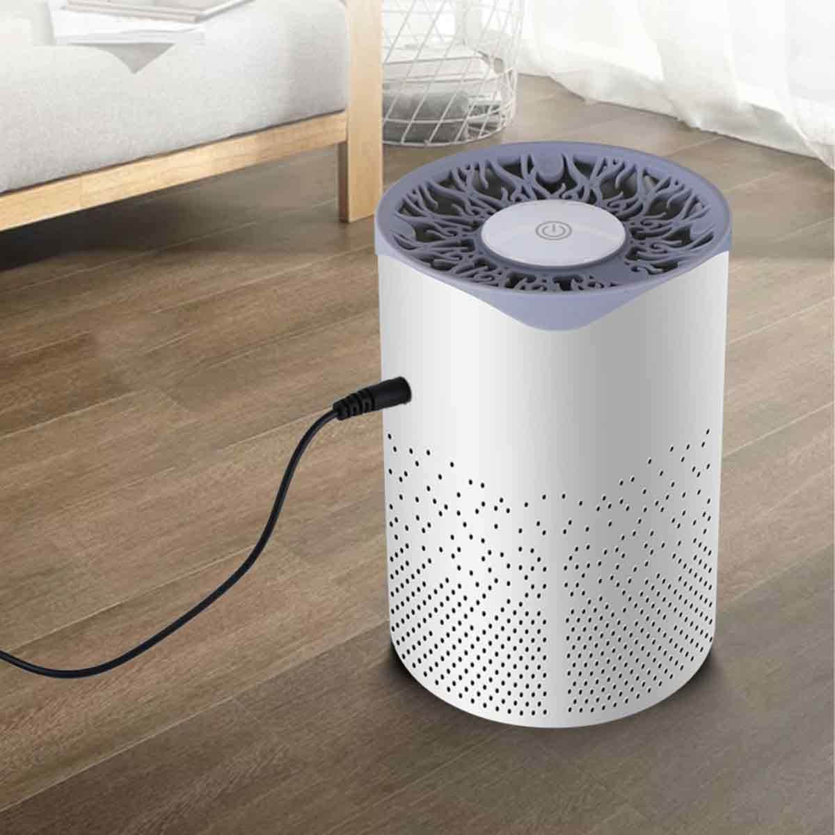Ein weißer und grauer Moskitokiller mit einem schwarzen Kabel, das auf einem Holzboden eingesteckt ist.