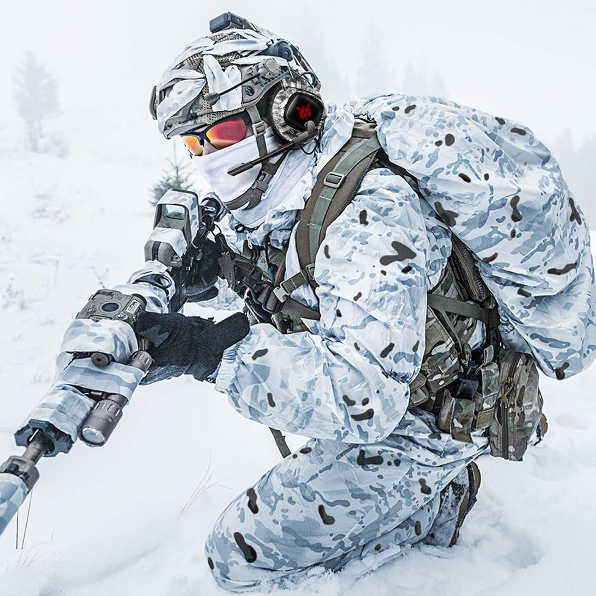 Soldat in weißer Tarnkleidung kniet im Schnee, Gewehr haltend, verschneiter Hintergrund.