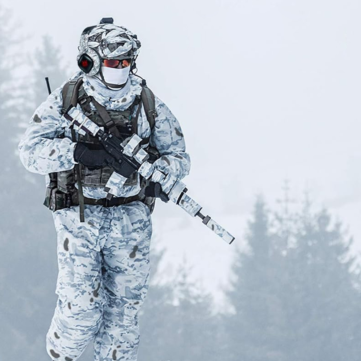 Soldat in Wintertarnung mit Gewehr in verschneiter Umgebung, verschwommener Hintergrund.