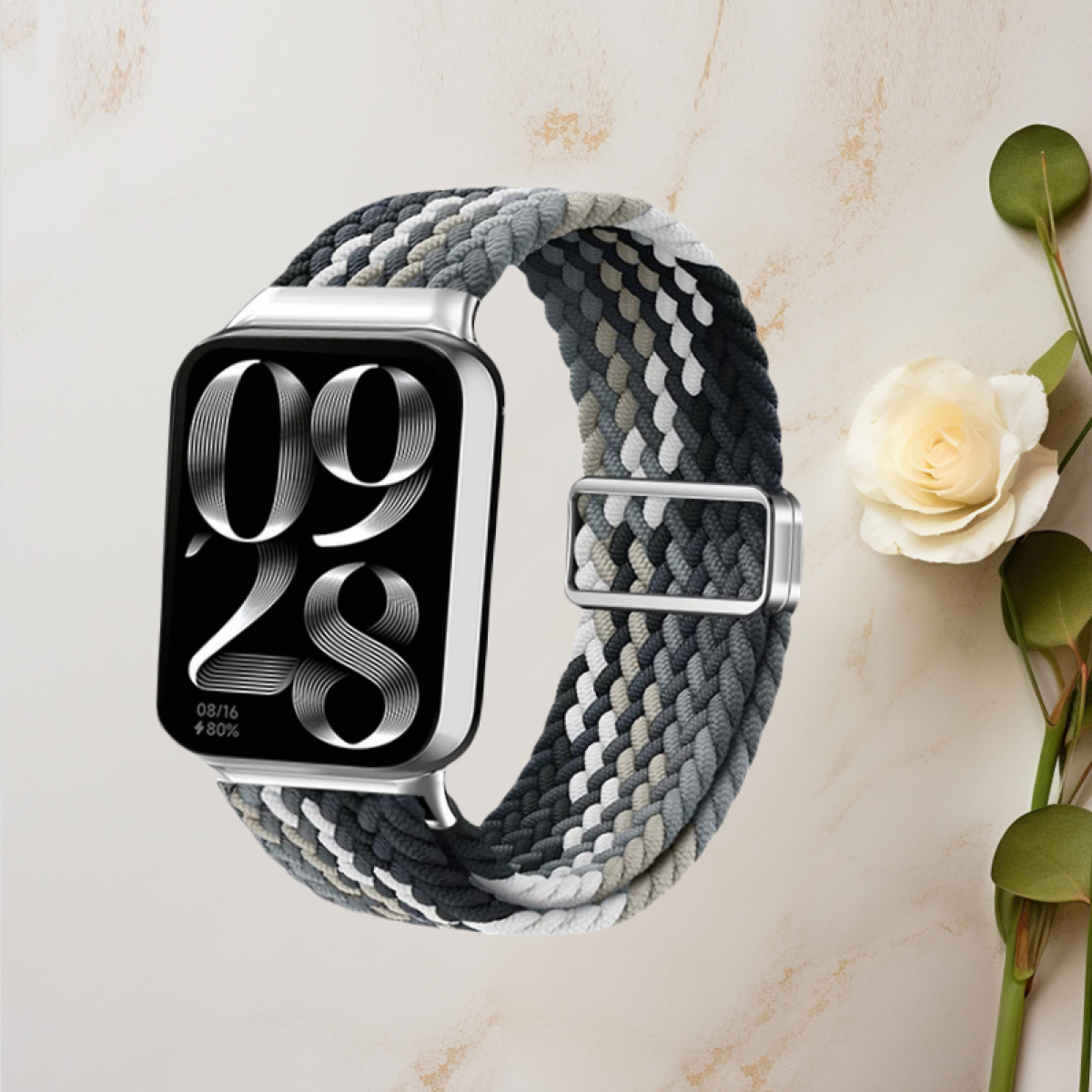 Uno smartwatch con schermo in bianco e nero, che mostra data e ora. L'orologio ha un cinturino intrecciato.