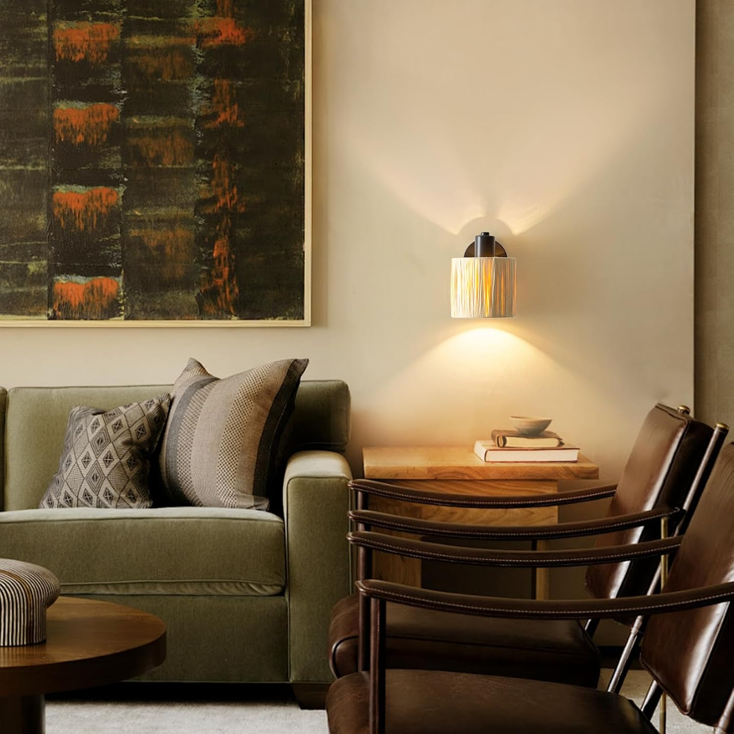 Salon z zieloną sofą, obrazami, krzesłami i lampą.