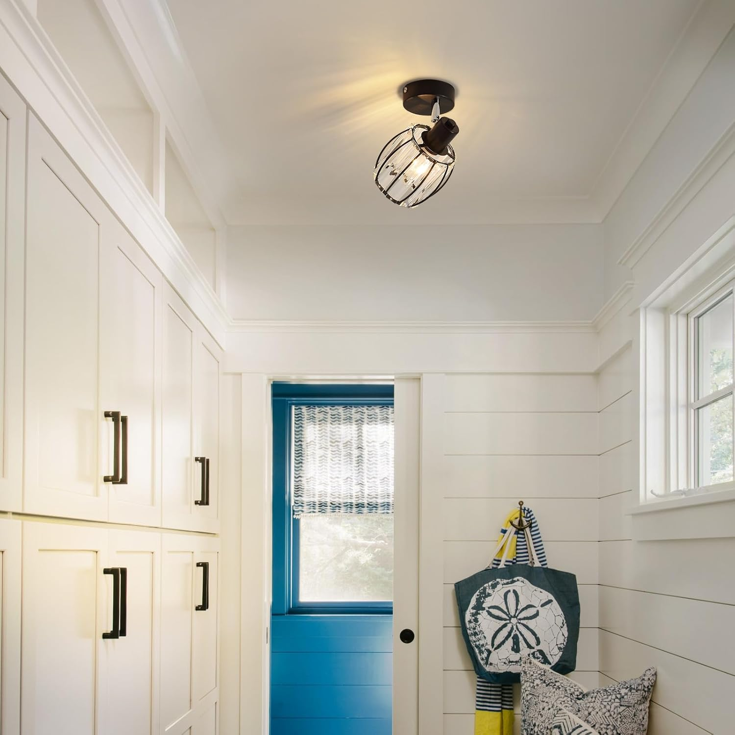 Biały korytarz z białymi szafkami, niebieskimi drzwiami i czarną oprawą oświetleniową na suficie.