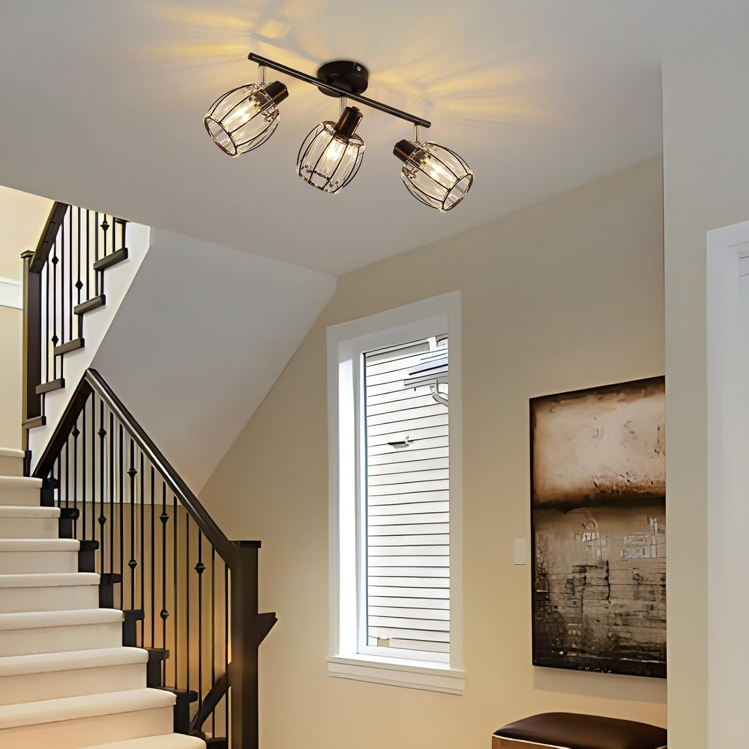 Oprawa oświetleniowa sufitowa z trzema światłami w klatkach, w korytarzu ze schodami.