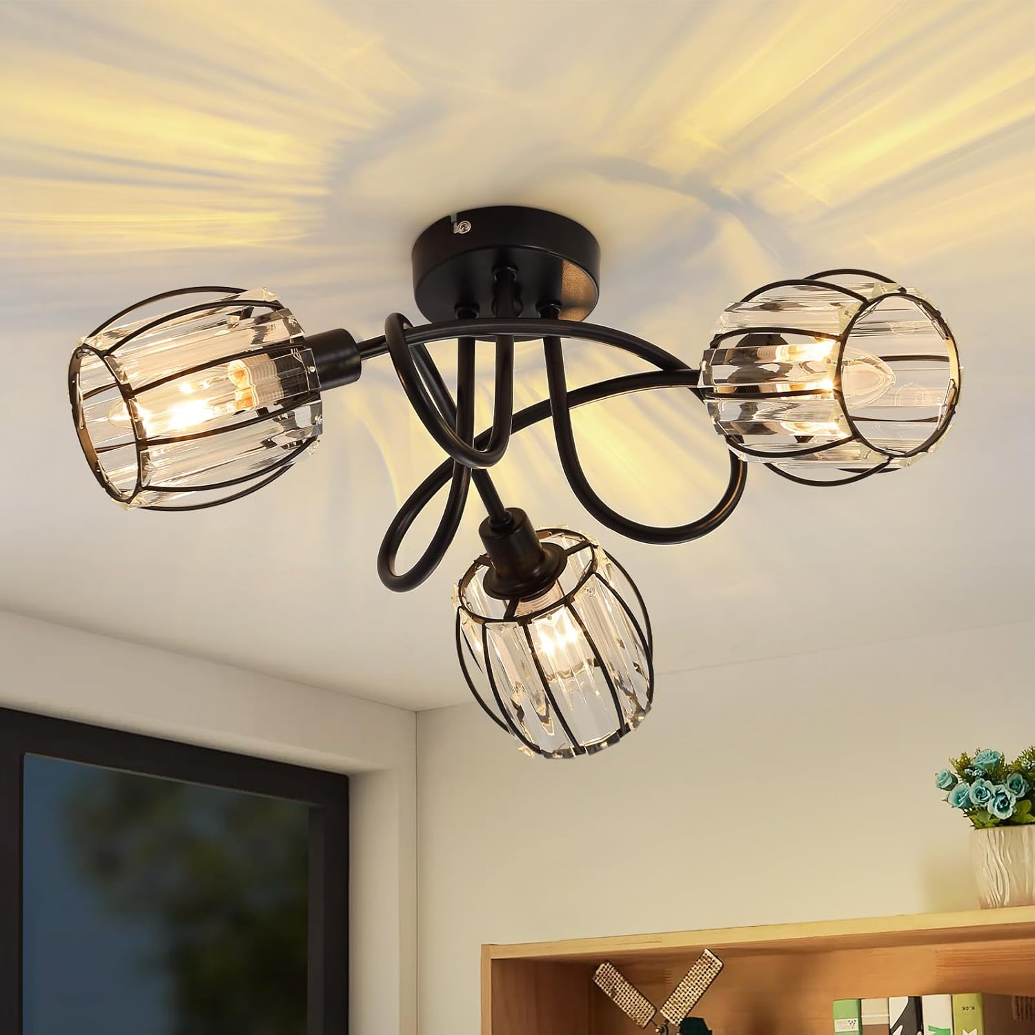 Lampa sufitowa z trzema kloszami z przezroczystego szkła. Czarna metalowa rama i biały sufit. Światło jest włączone.