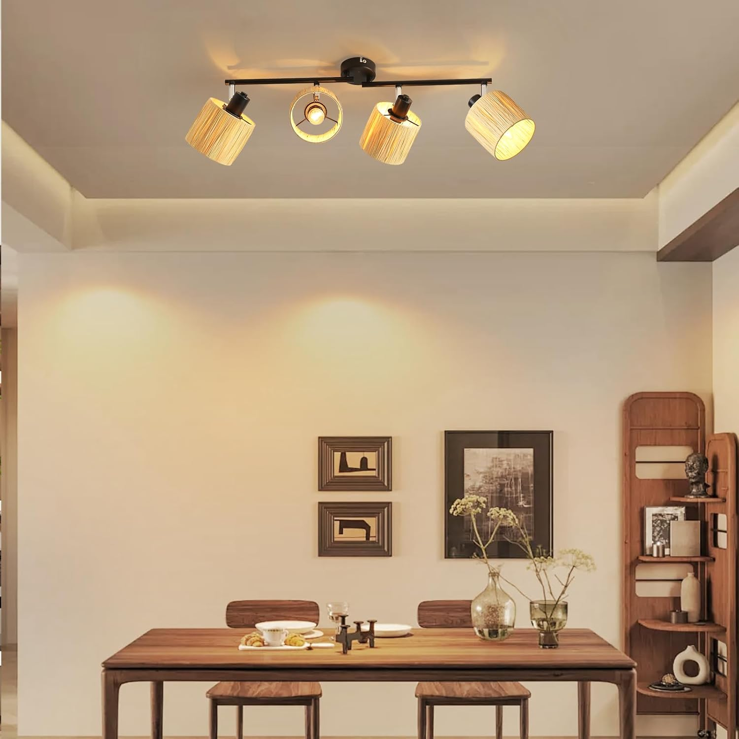 Jadalnia z długim drewnianym stołem i lampą sufitową z czterema lampami. Ramki i dekoracje.