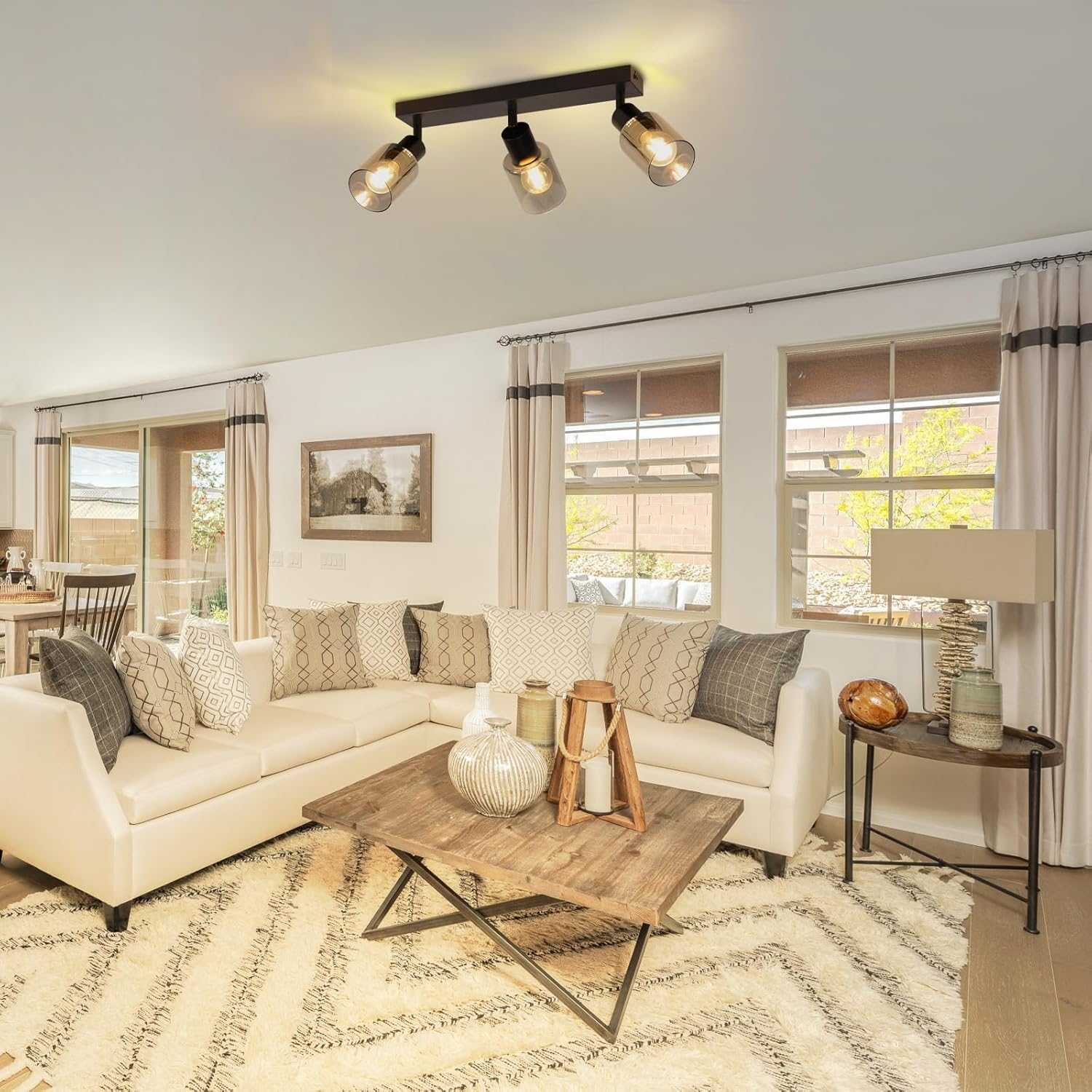 Salon z białą sofą, stolikiem kawowym i trzema reflektorami. Widoczne są również okna i dywan.