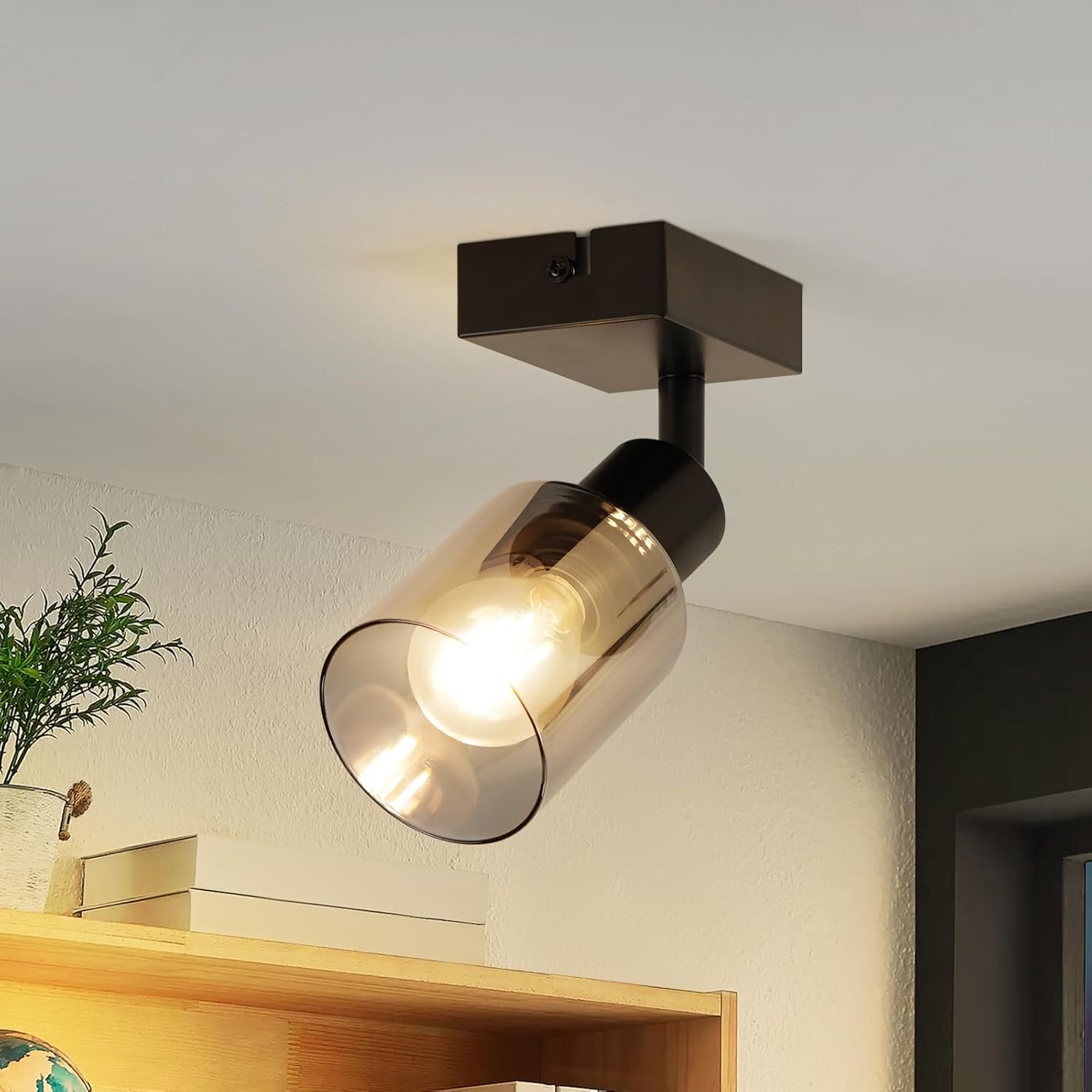 Czarny reflektor na białym suficie, żarówka świeci, w pokoju.