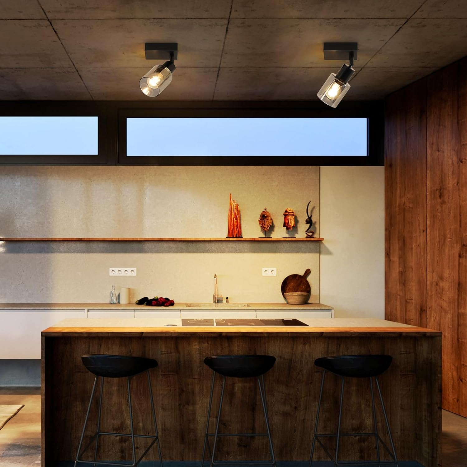 Nowoczesna kuchnia z dwoma reflektorami sufitowymi. Betonowy sufit, drewniana wyspa, stołki. Neutralne odcienie.