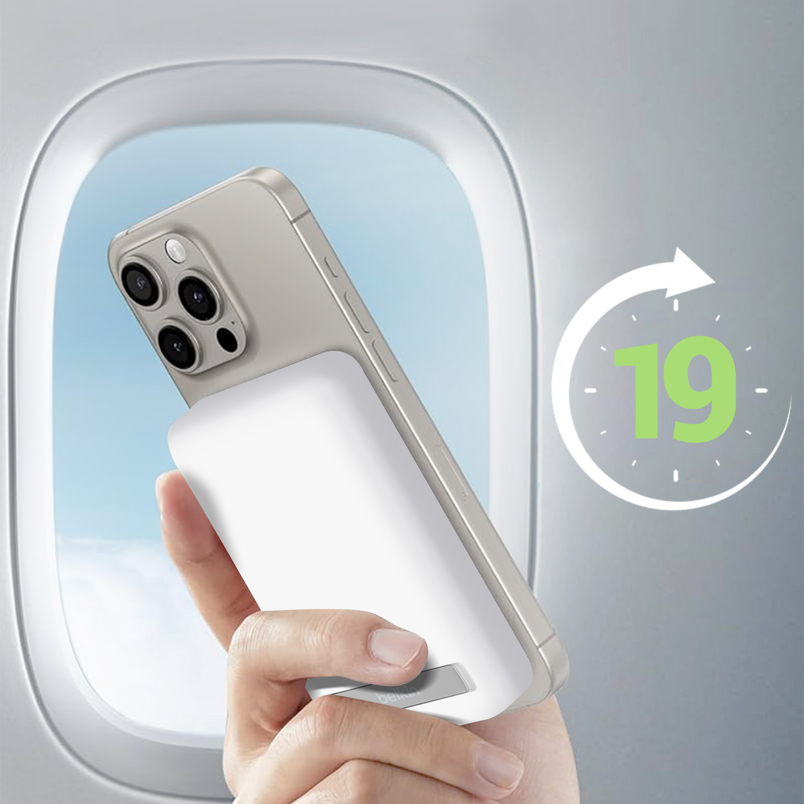 Een hand die een telefoon vasthoudt met een witte oplader. De scène is een vliegtuigraam.