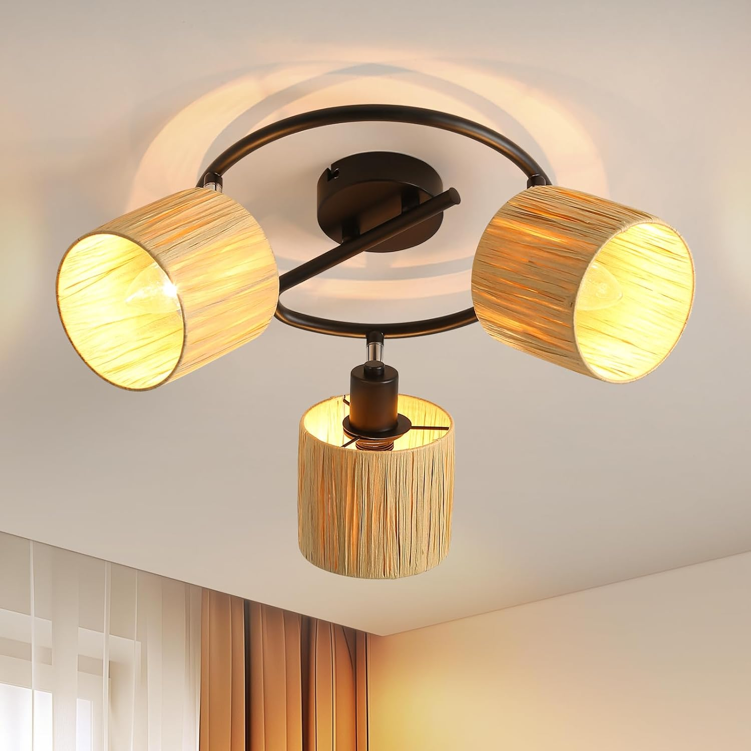 Lampa sufitowa z trzema beżowymi, cylindrycznymi kloszami, z czarną konstrukcją centralną na białym suficie.