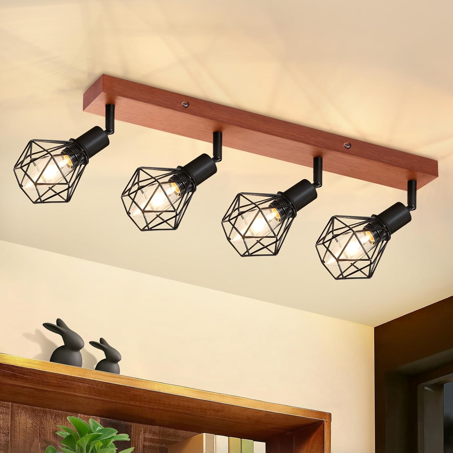 Cztery lampy sufitowe na drewnianej belce. Każda lampa ma metalową klatkę z żarówką.