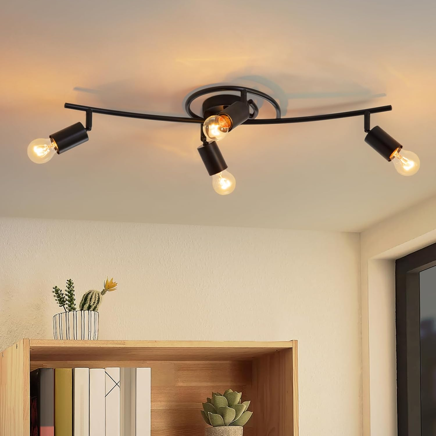 Oprawa oświetleniowa sufitowa z czterema żarówkami. Światło jest czarne, zamontowane na suficie, z rośliną w tle.