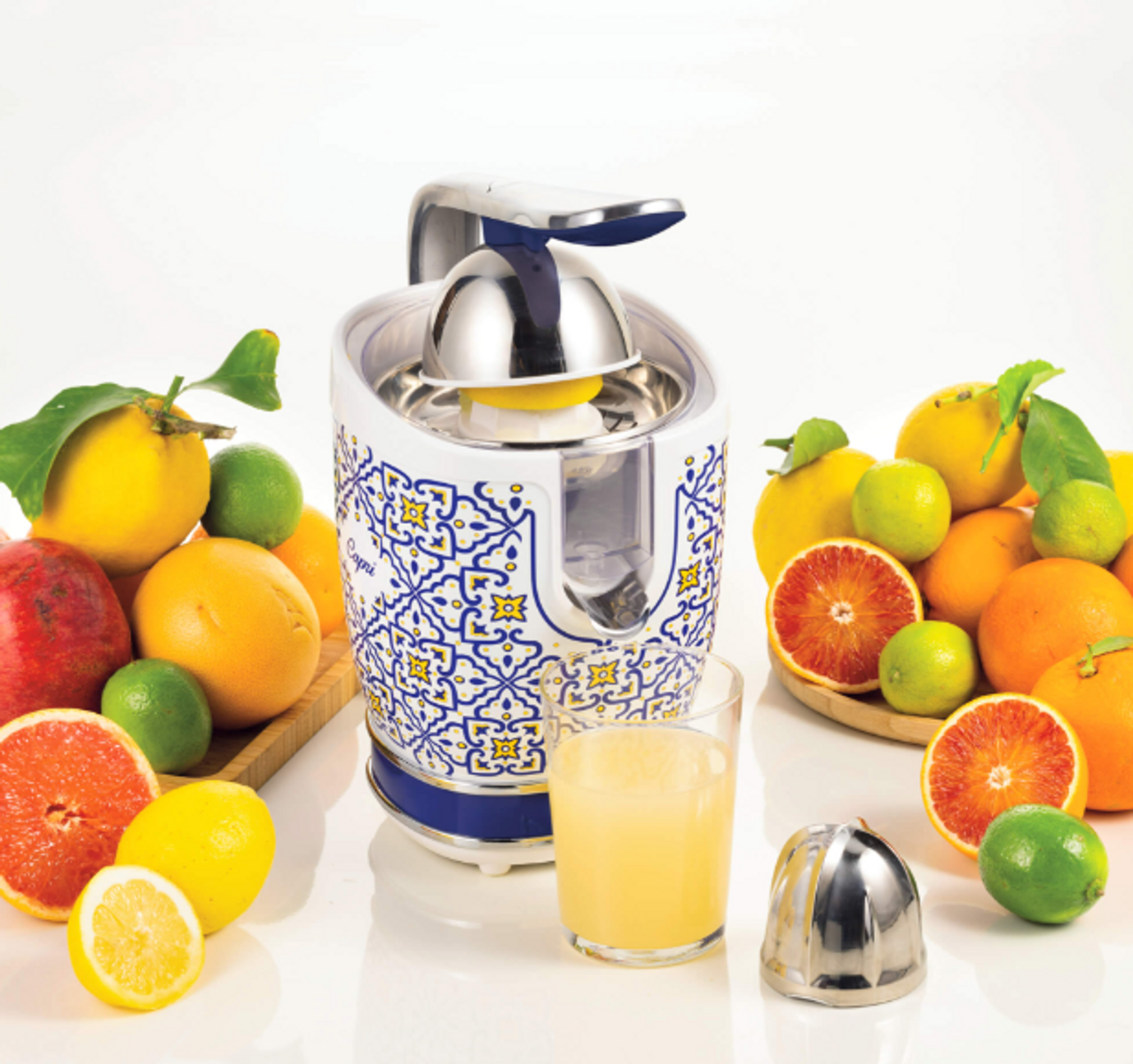 Wyrażacz do cytrusów z cytrynami, pomarańczami i limonkami oraz szklanka soku. Niektóre pomarańcze są przecięte.