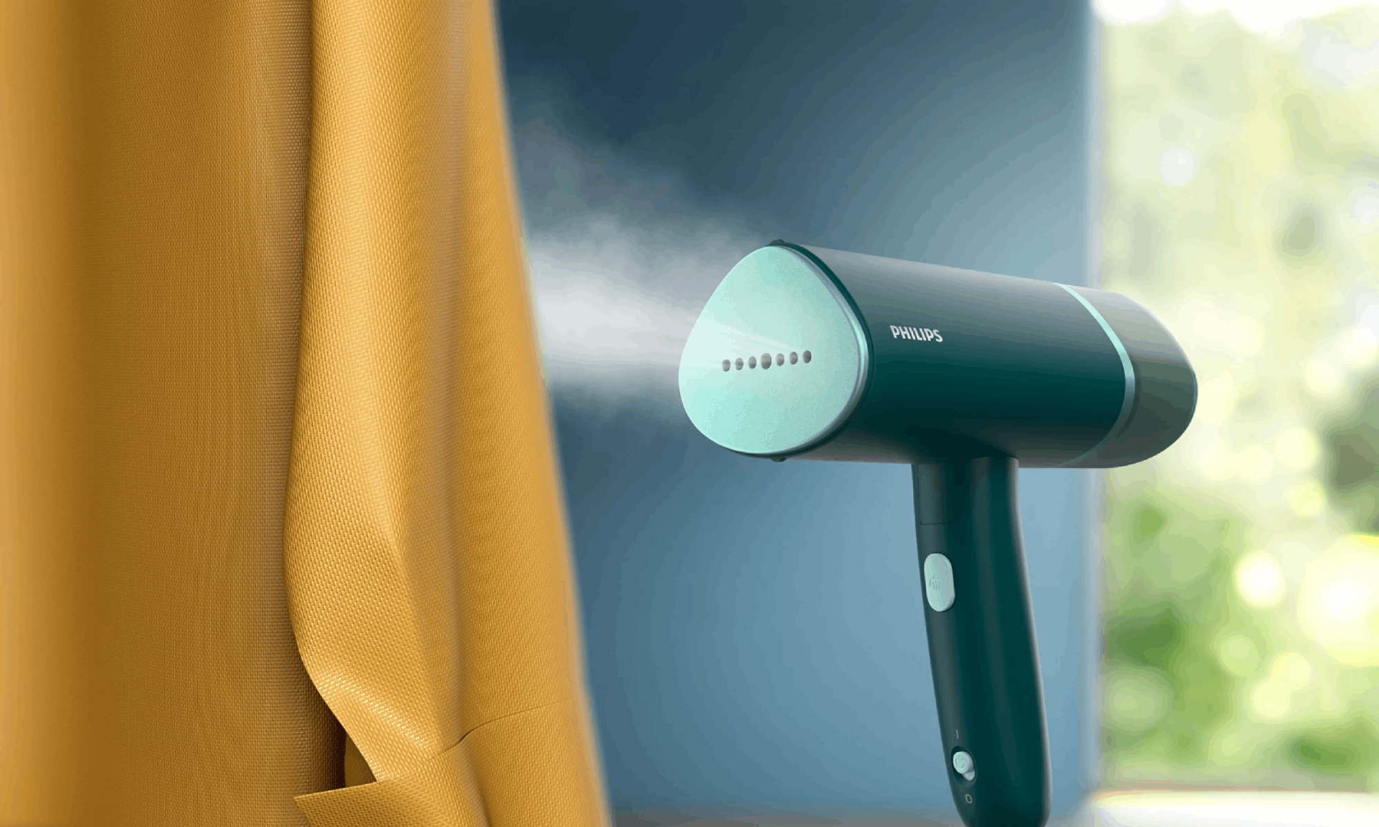 Türkis-Handdampfer mit Dampf. Gelber Vorhang und blaue Wand im Hintergrund.