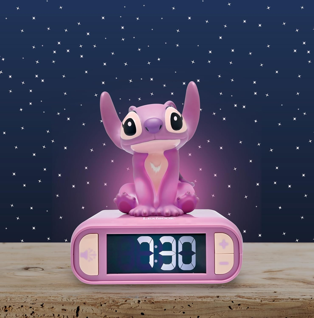 Réveil Stitch rose avec affichage numérique, figurine Stitch dessus, fond d'étoiles bleues.
