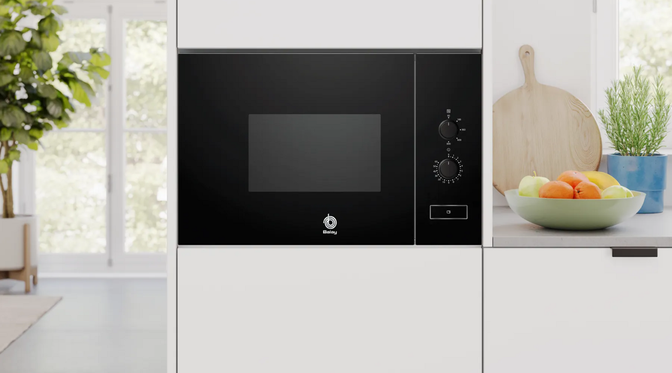 Wbudowana czarna kuchenka mikrofalowa z elementami sterującymi po prawej stronie. Biała kuchnia z owocami.
