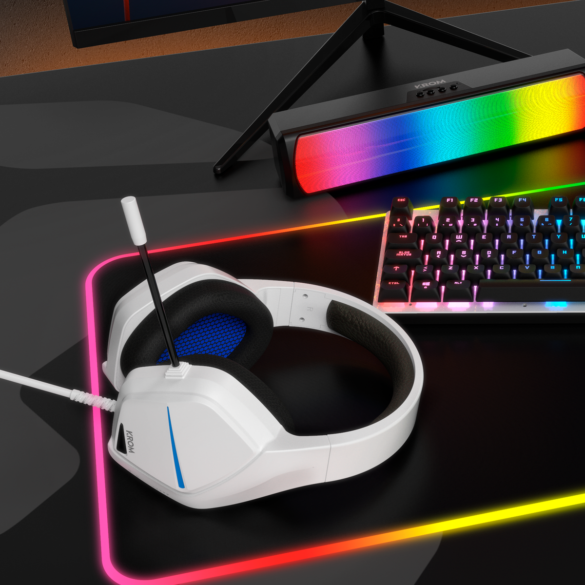 Biały zestaw słuchawkowy do gier z mikrofonem spoczywa na biurku z klawiaturą i soundbarem.