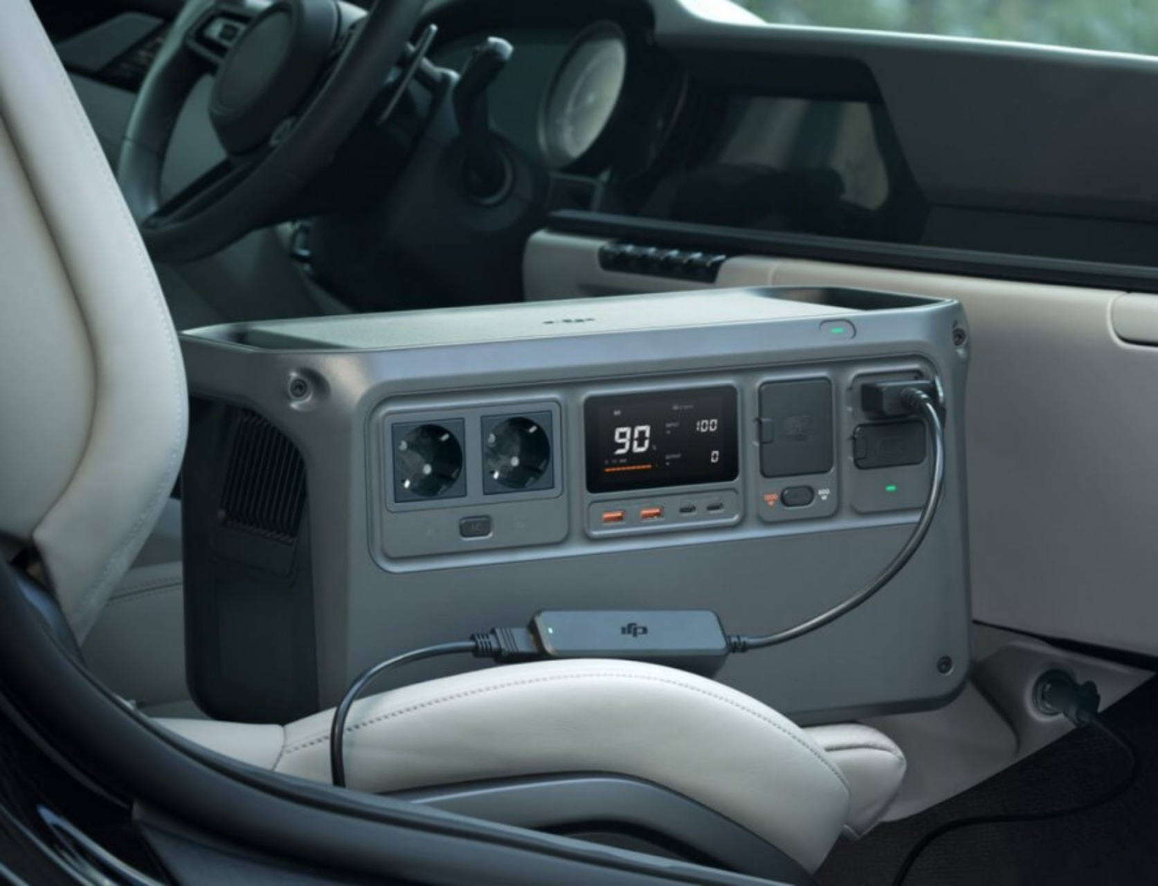 Wnętrze samochodu z elektrownią na tylnym siedzeniu, podłączoną do urządzenia.