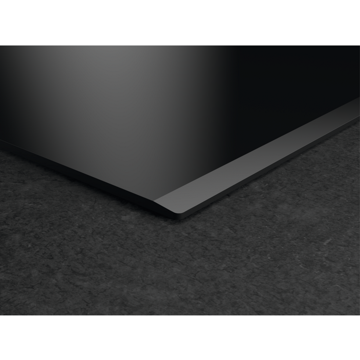 Placa de inducción negra sobre superficie de piedra gris oscuro. Forma rectangular.