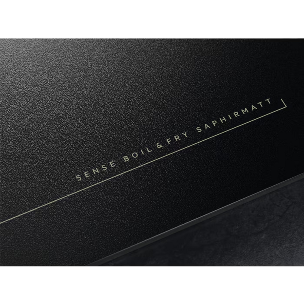 Czarna powierzchnia ze złotym tekstem: SENSE BOIL & FRY SAPHIRMATT. Powierzchnia ma szorstką teksturę.