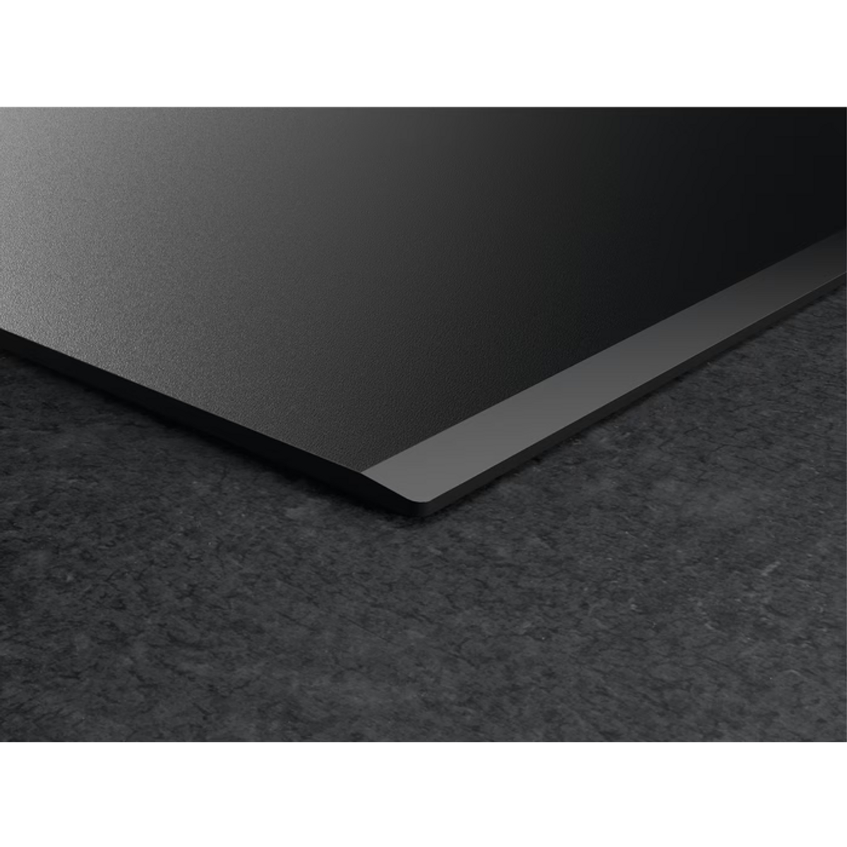 Czarna płyta indukcyjna, zbliżenie z ciemnoszarą, kamienną powierzchnią.