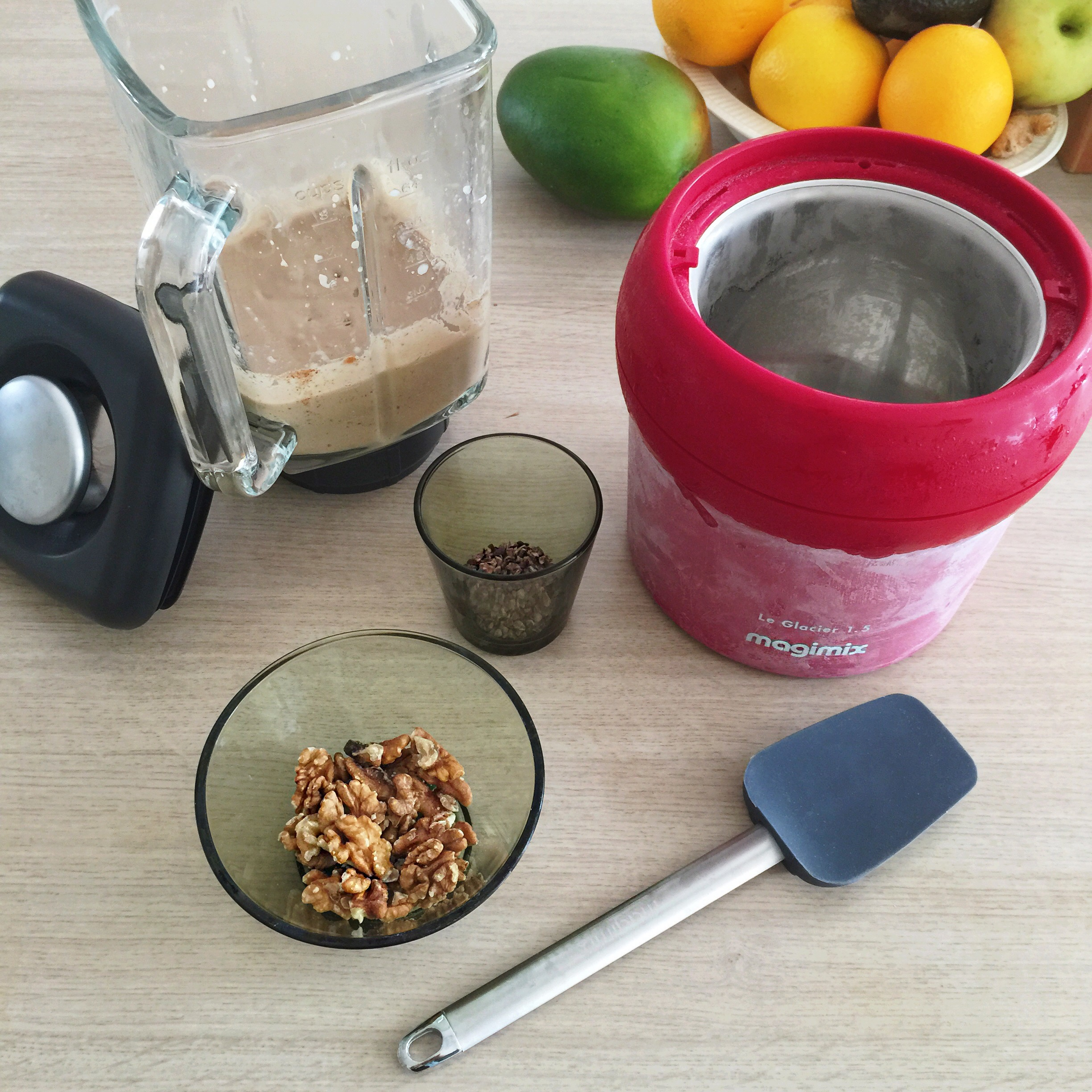 Ingrédients pour un smoothie : mixeur, noix, sorbetière et fruits sur une table en bois.
