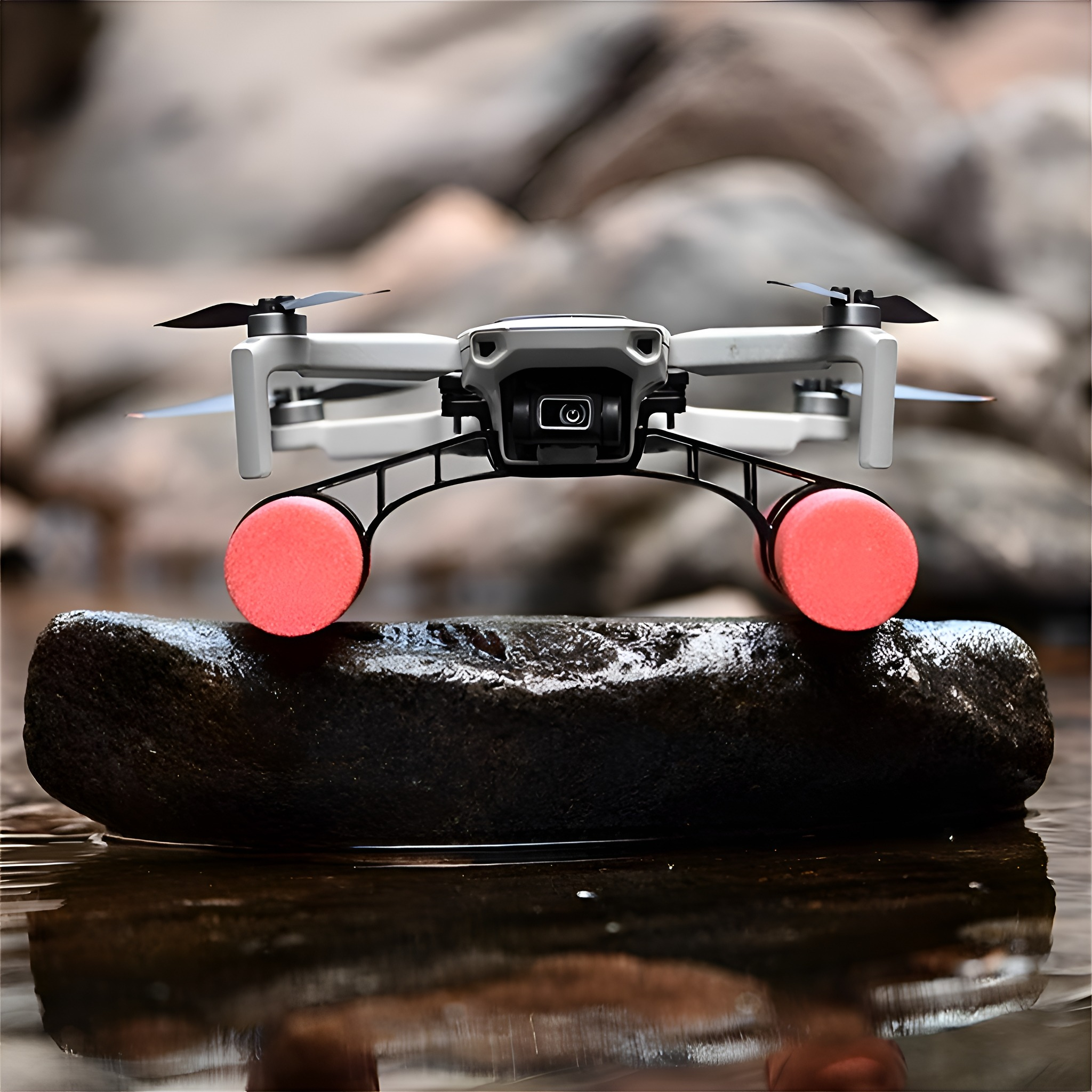 Eine graue Drohne mit rosa Schwimmern liegt auf einem Felsen im Wasser.