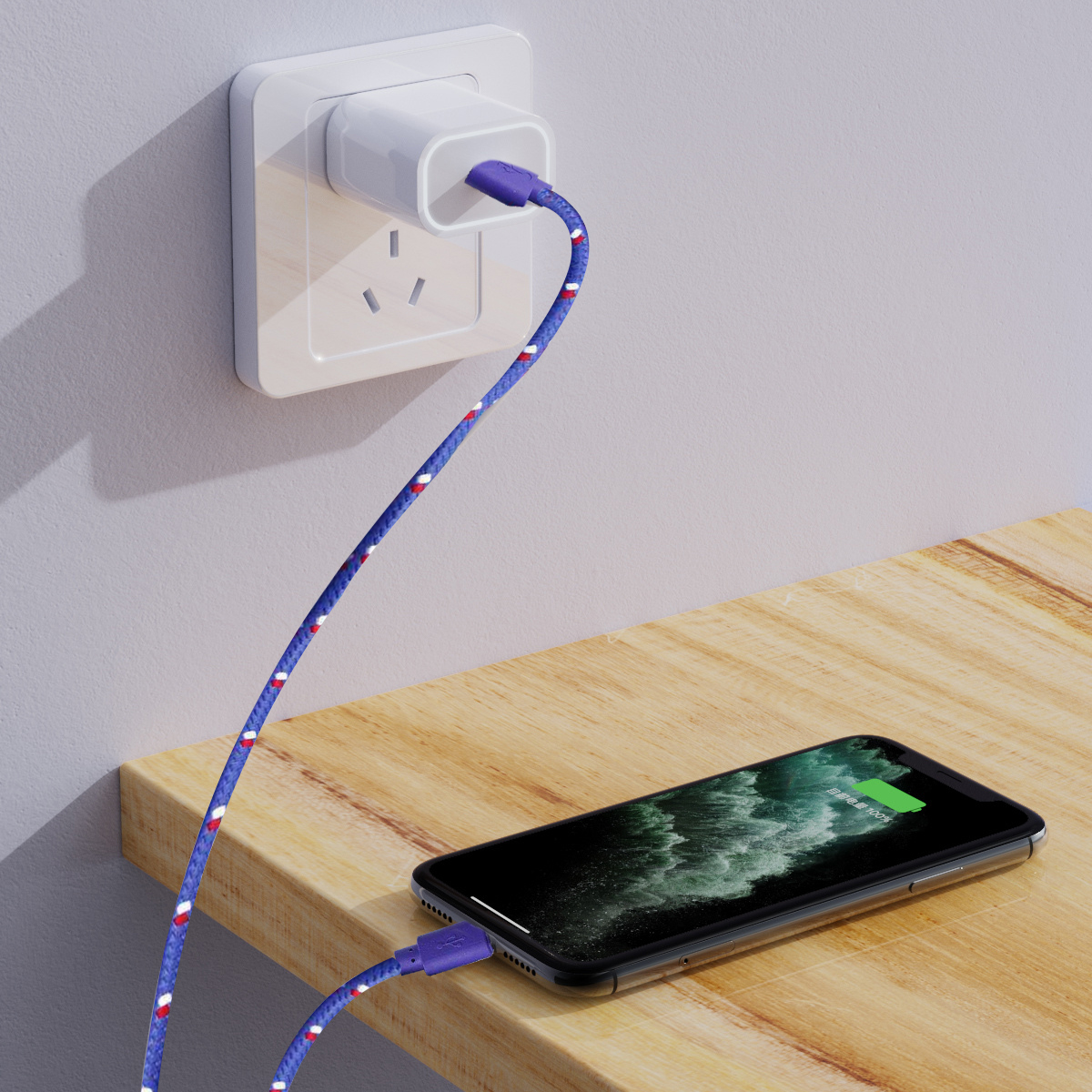 Ein Telefon, das mit einem blau-weißen Kabel geladen wird, das an einer Steckdose auf einem Holztisch angeschlossen ist.