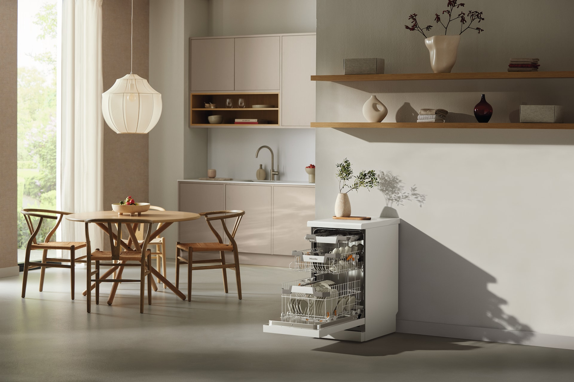 Küche mit geöffneter Spülmaschine. Runder Holztisch, Stühle und Küchenschränke, mit Fensterlicht.