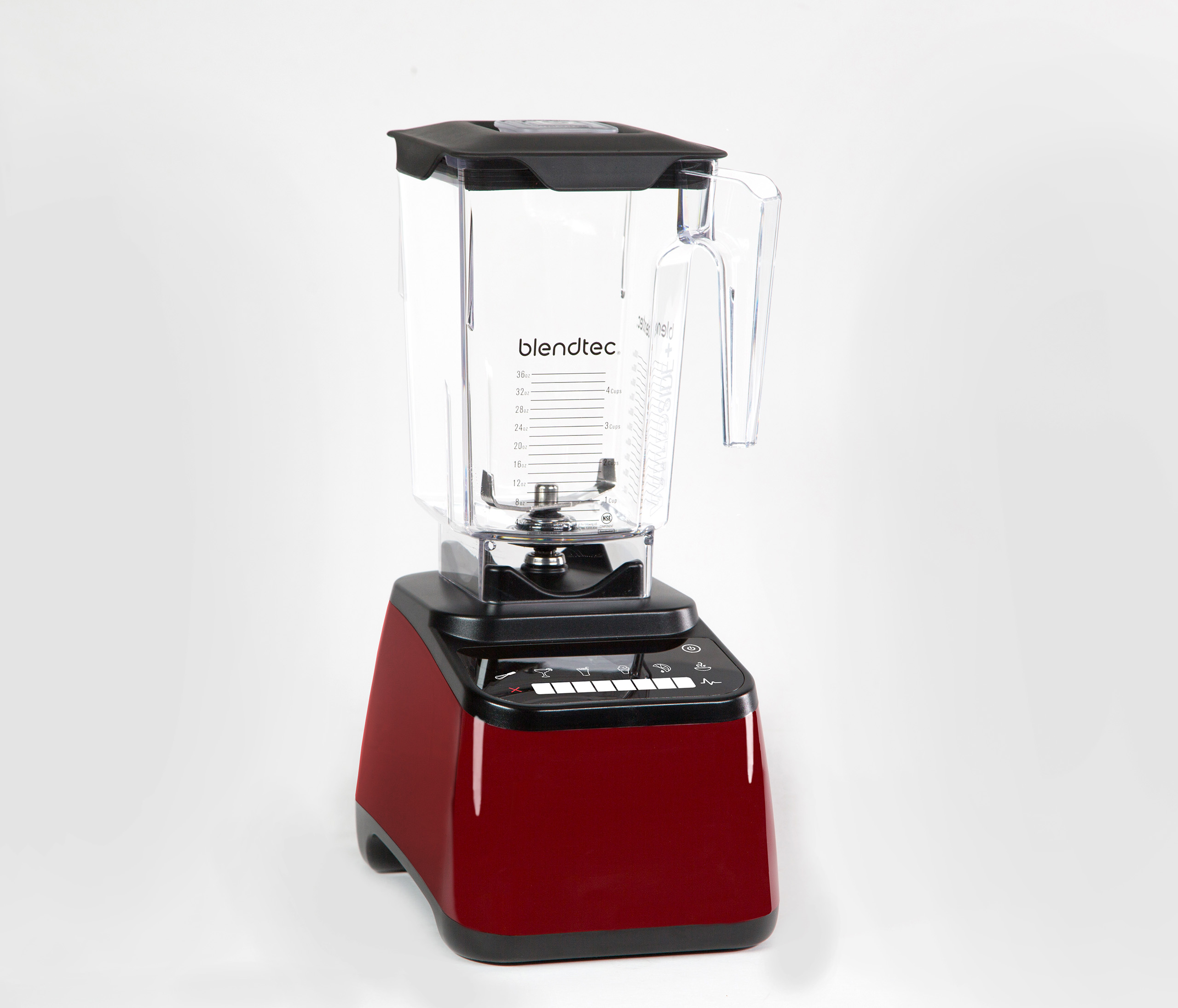 Un frullatore Blendtec rosso su sfondo bianco. Ha un coperchio nero e un contenitore trasparente con misure.