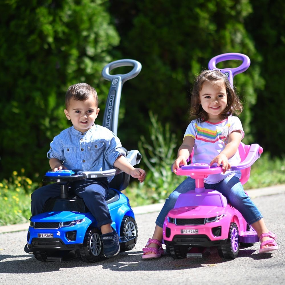 Dos niños en coches de juguete. Uno es azul, el otro es rosa. Ambos tienen manijas.