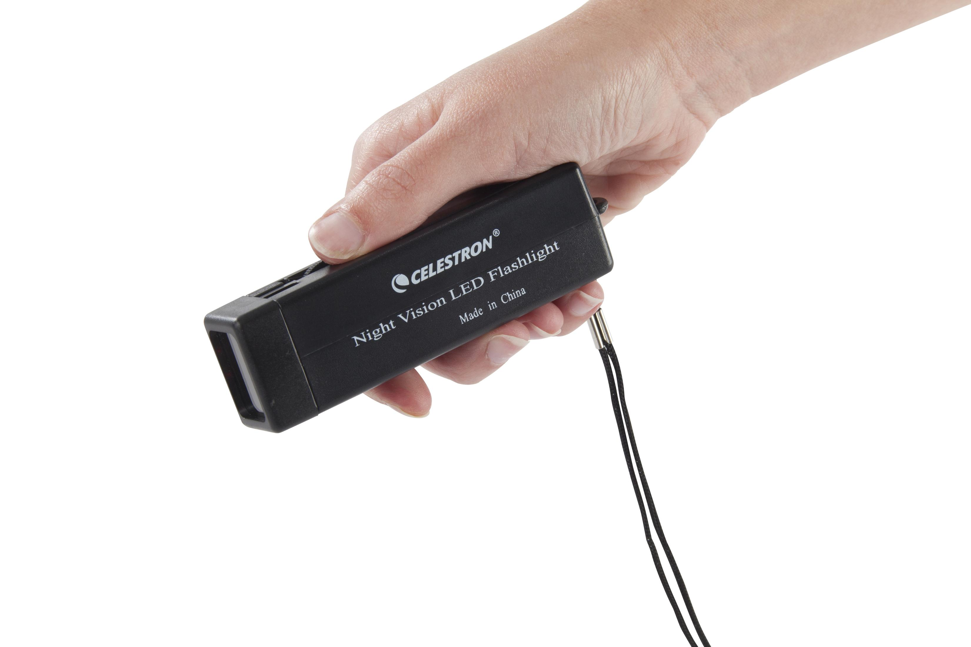 Hand, die eine schwarze Celestron Nachtsicht-LED-Taschenlampe mit schwarzem Umhängeband hält, auf weißem Hintergrund.
