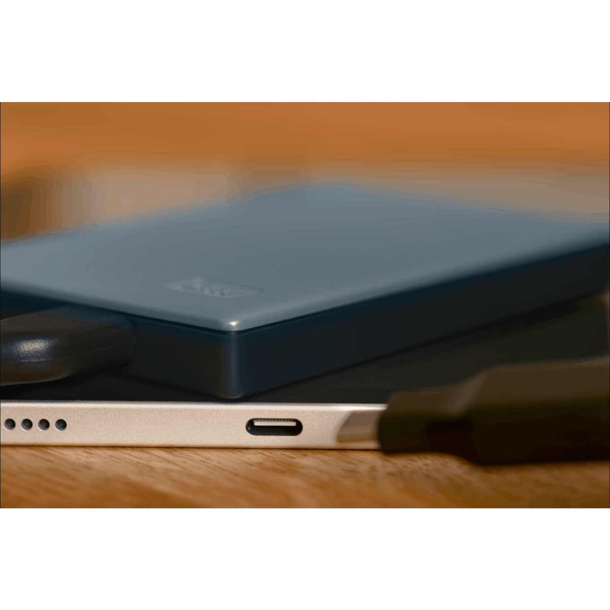 Ciemnoniebieski zewnętrzny dysk twardy podłączony do srebrnego tabletu.