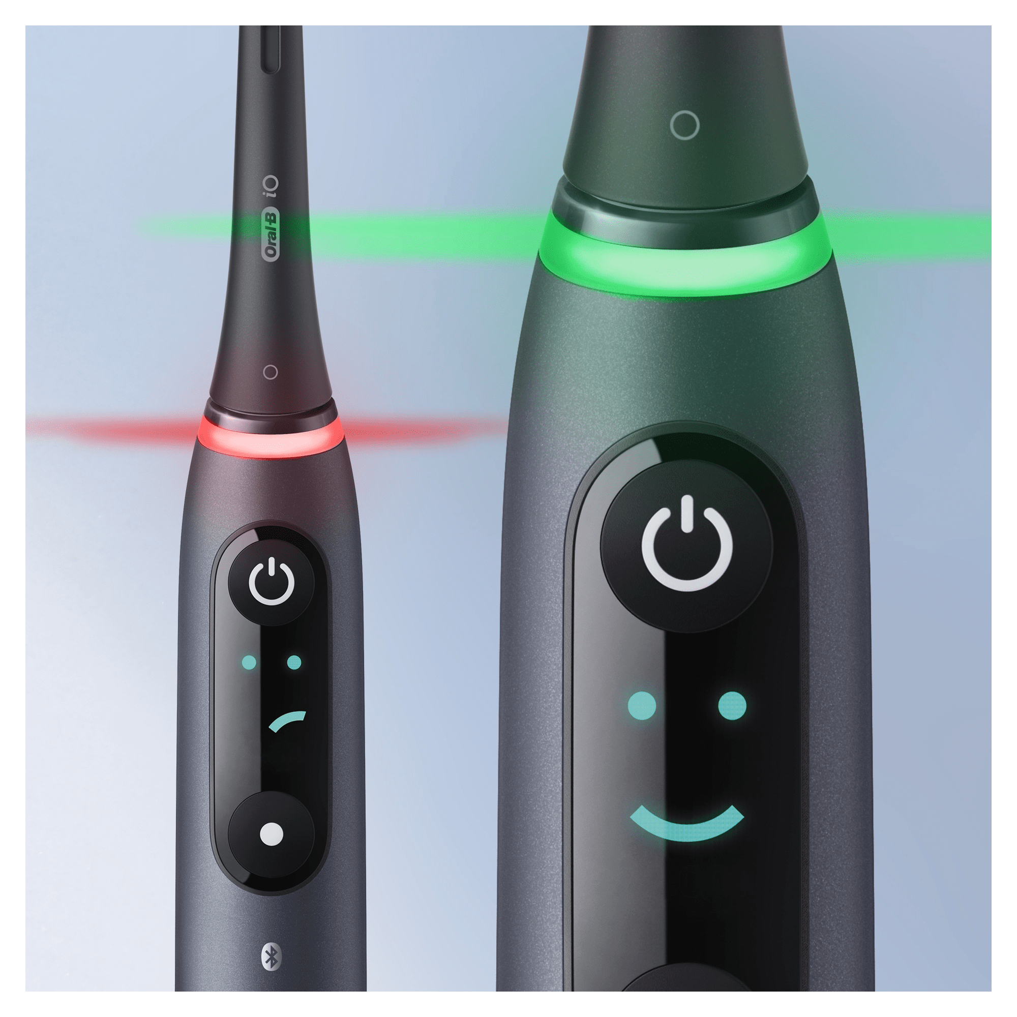 Dos cepillos de dientes eléctricos, uno con luz roja, otro con luz verde, botones de encendido.