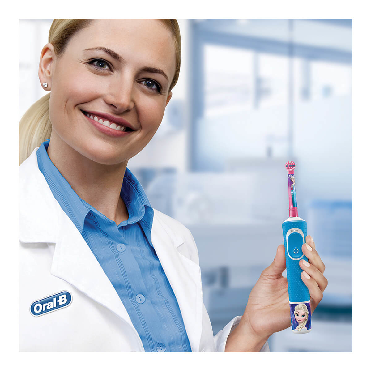 Donna che tiene uno spazzolino blu con un design di Elsa. Camice bianco e sfondo.