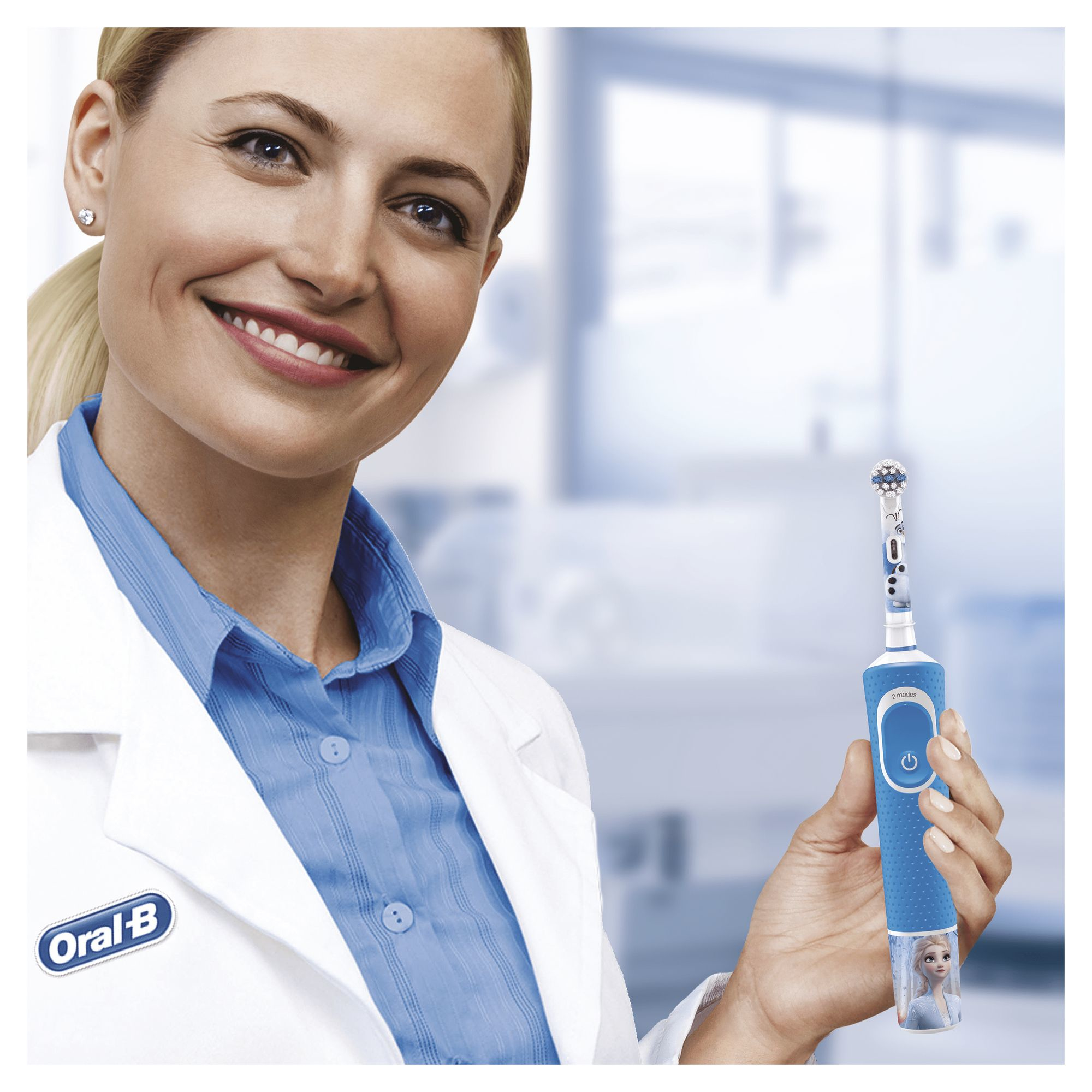 Donna in camice tiene in mano uno spazzolino elettrico blu Oral-B con design Frozen.