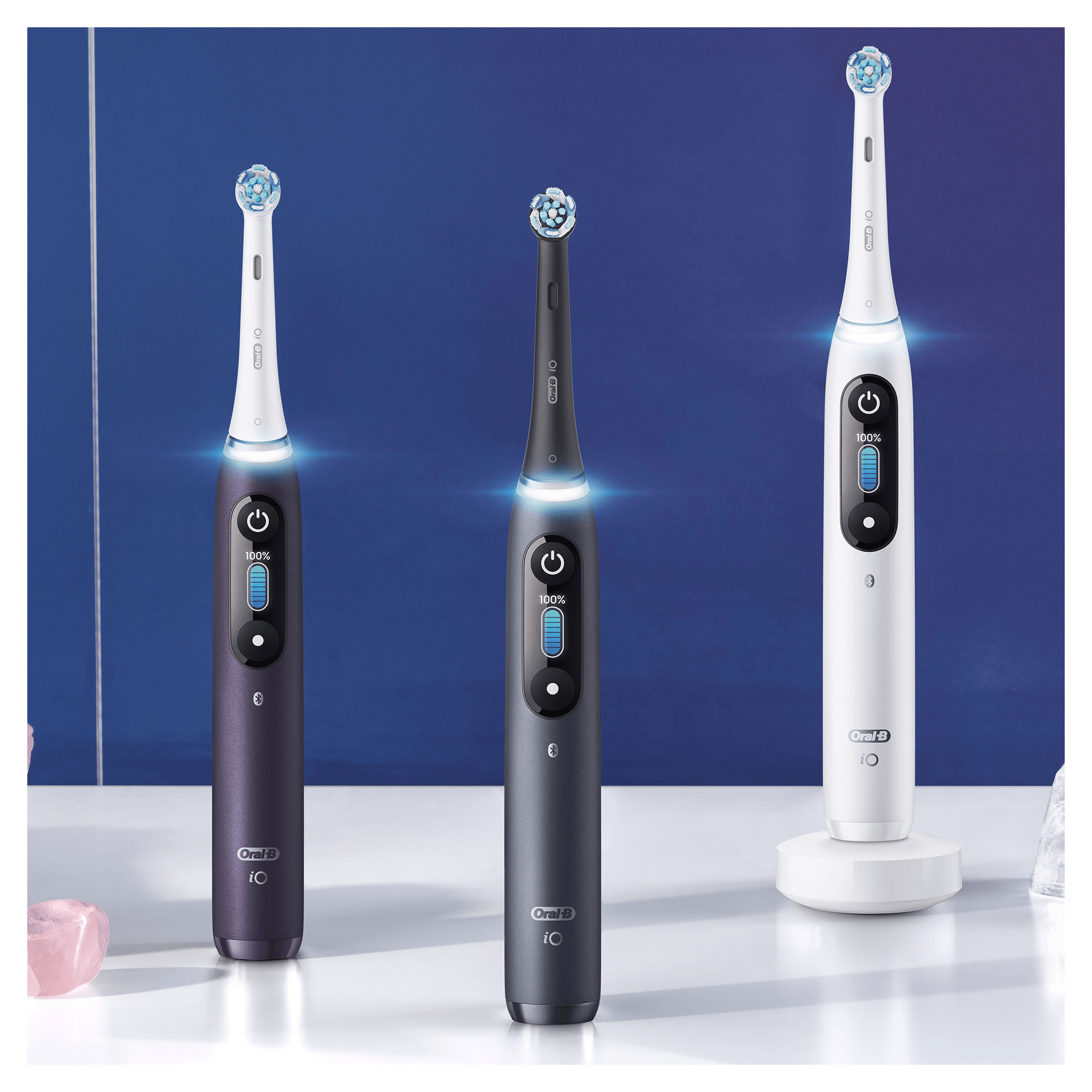 Tres cepillos de dientes Oral-B IO en diferentes colores. Tienen un botón de encendido y un indicador de batería.