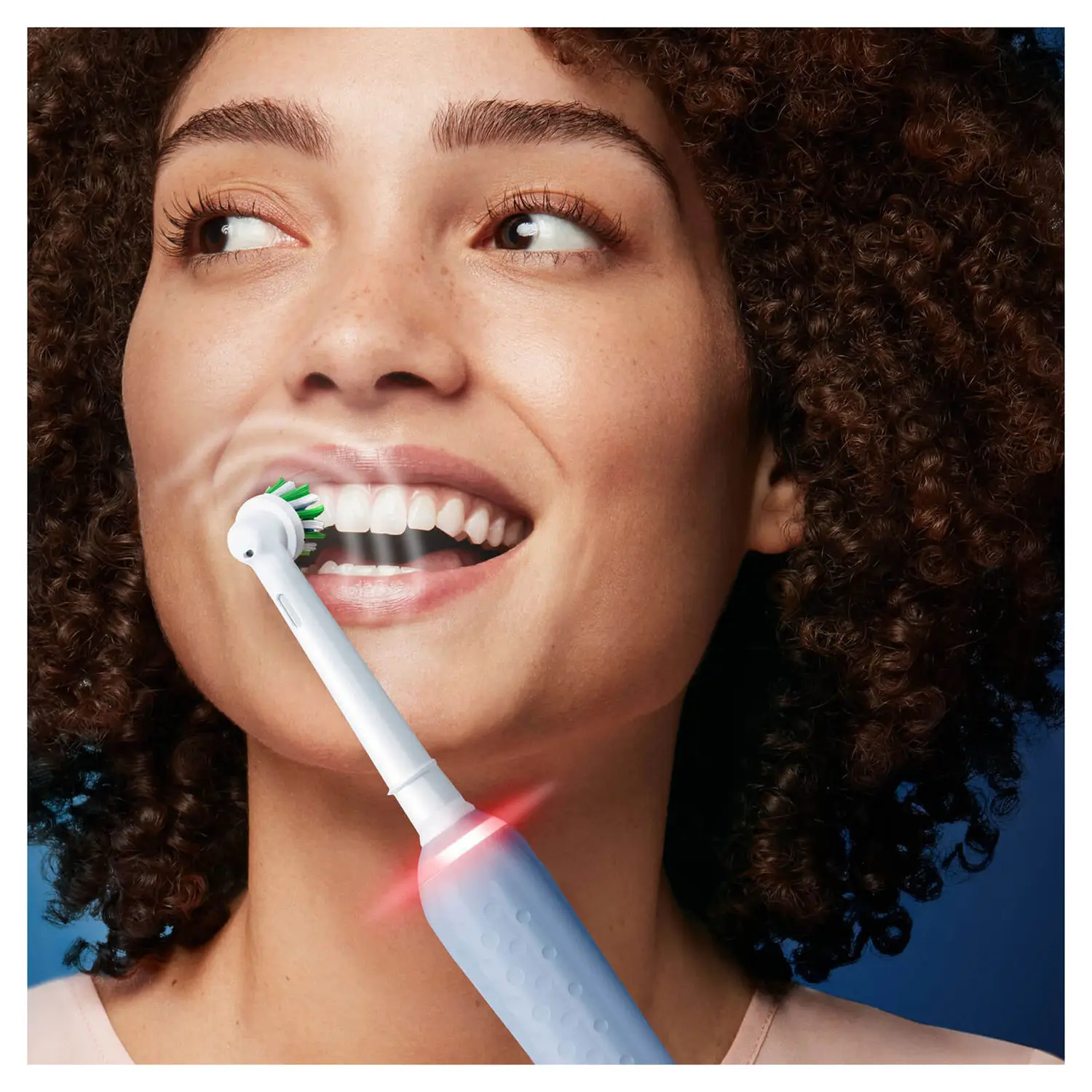 Kobieta myjąca zęby elektryczną szczoteczką Oral-B, pokazująca główkę szczoteczki.