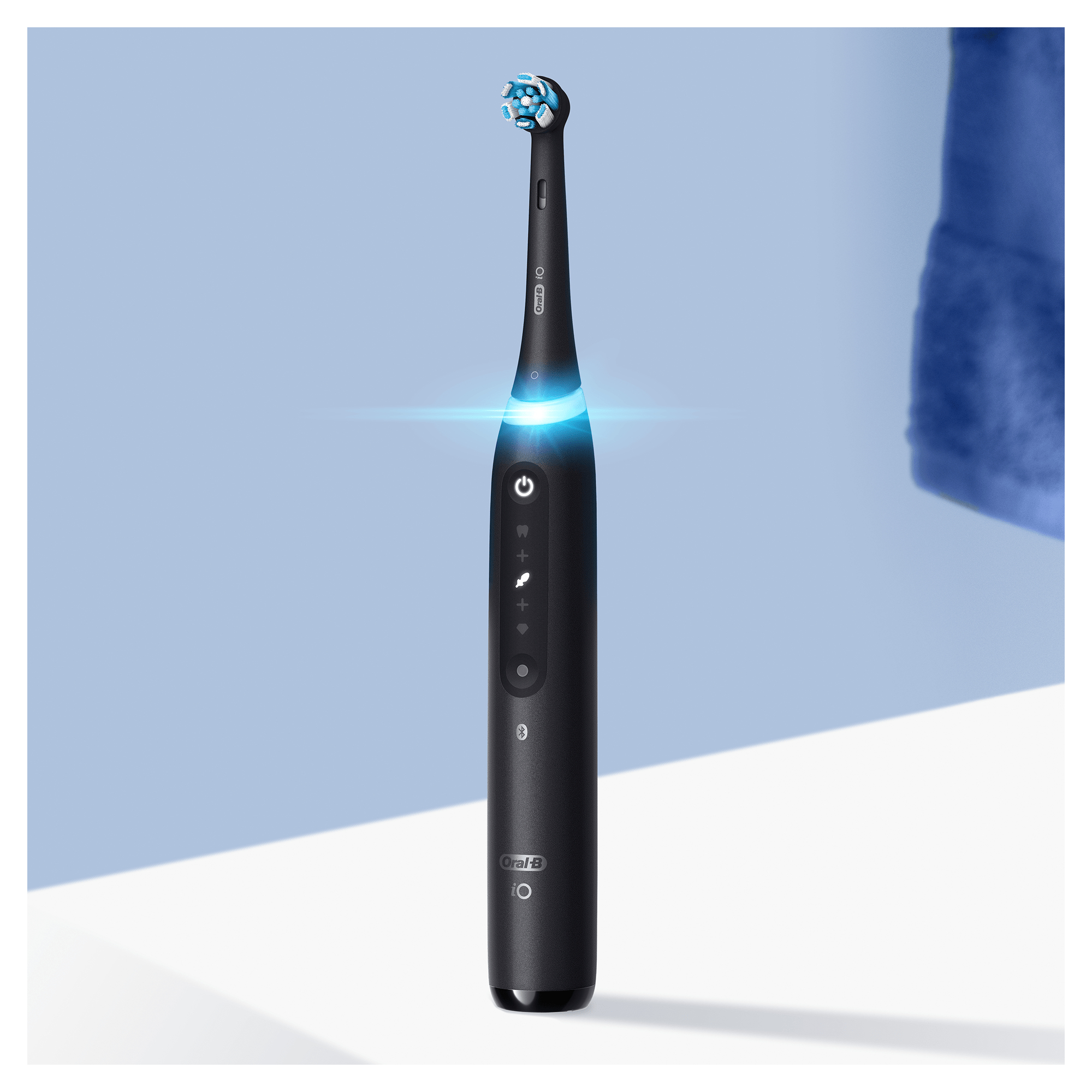 Schwarze elektrische Zahnbürste mit Licht und Knöpfen, vor blauem Hintergrund.
