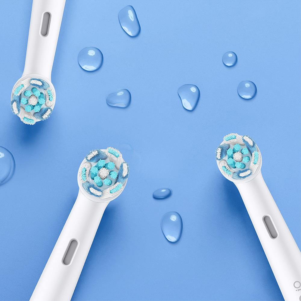 Múltiples cabezales de cepillo de dientes eléctrico y gotas de agua sobre una superficie azul.