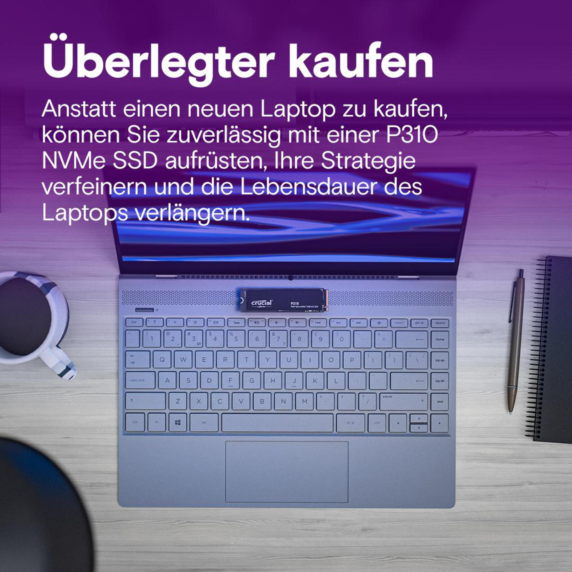 Laptop na drewnianym biurku z zainstalowanym dyskiem Crucial P310 NVMe SSD, kubek, długopis i notatnik.