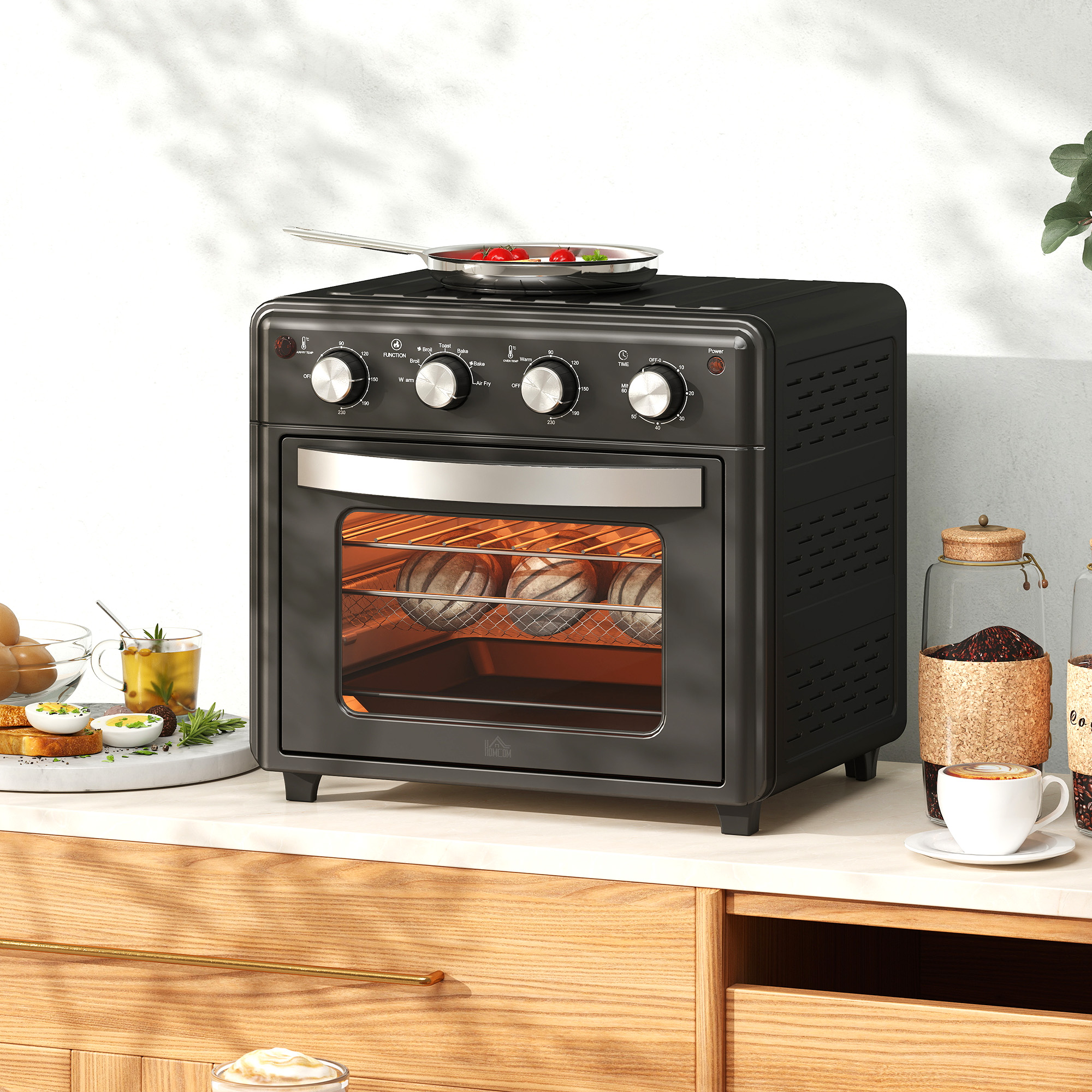 Horno freidora de aire negro con controles. Sartén dentro. Encimera blanca, fondo soleado.