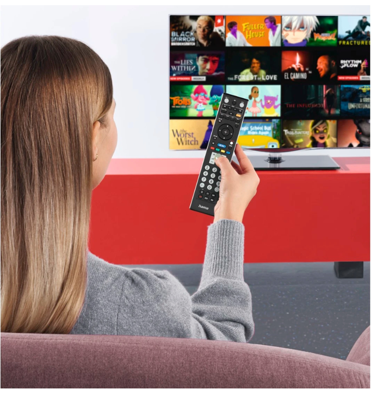 Kobieta trzymająca pilota do telewizora, oglądająca telewizję z tytułami filmów.